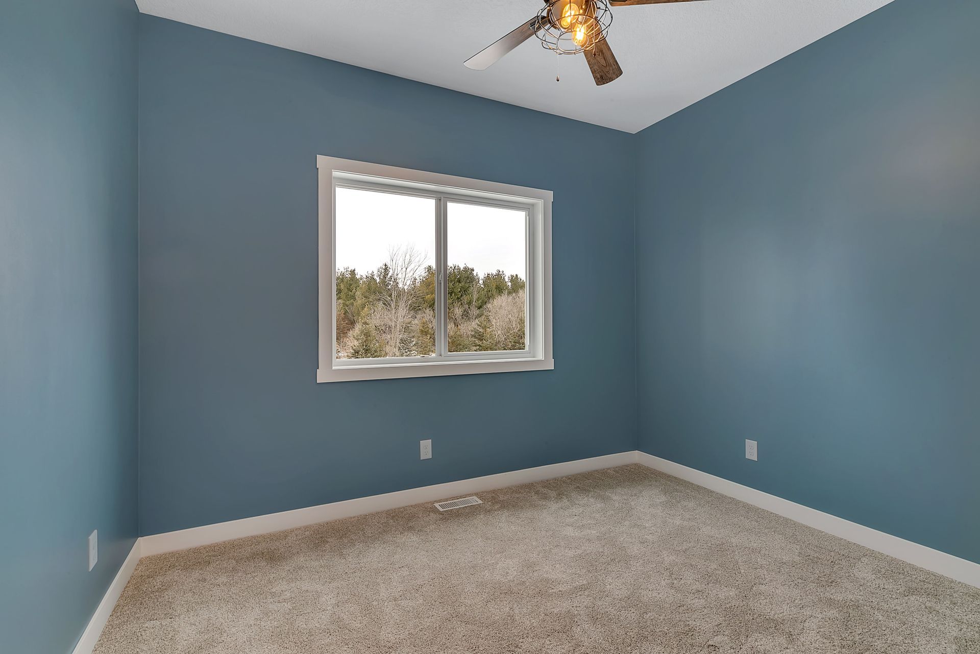 An empty bedroom with blue walls and a ceiling fan.