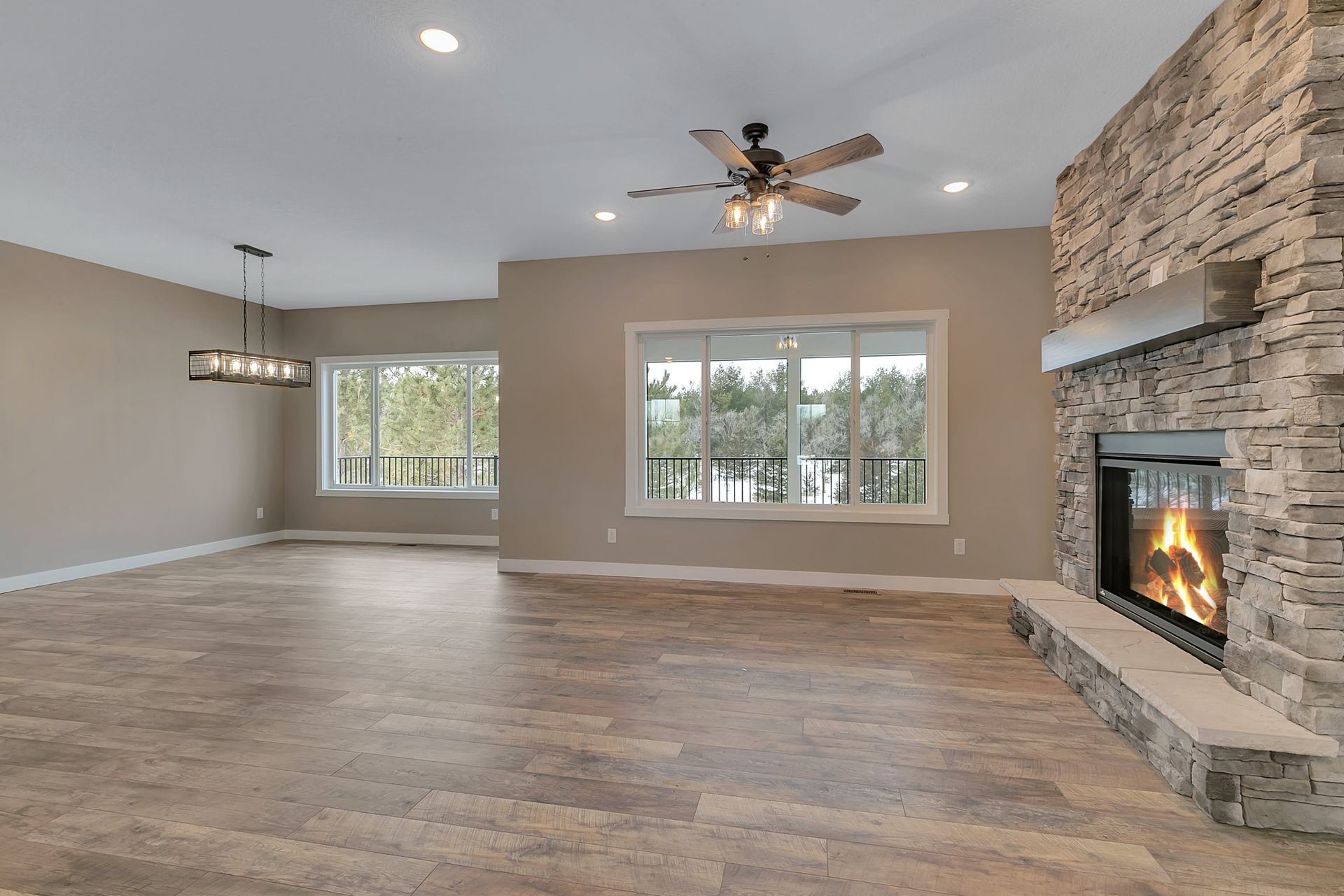 An empty living room with a fireplace and a ceiling fan.