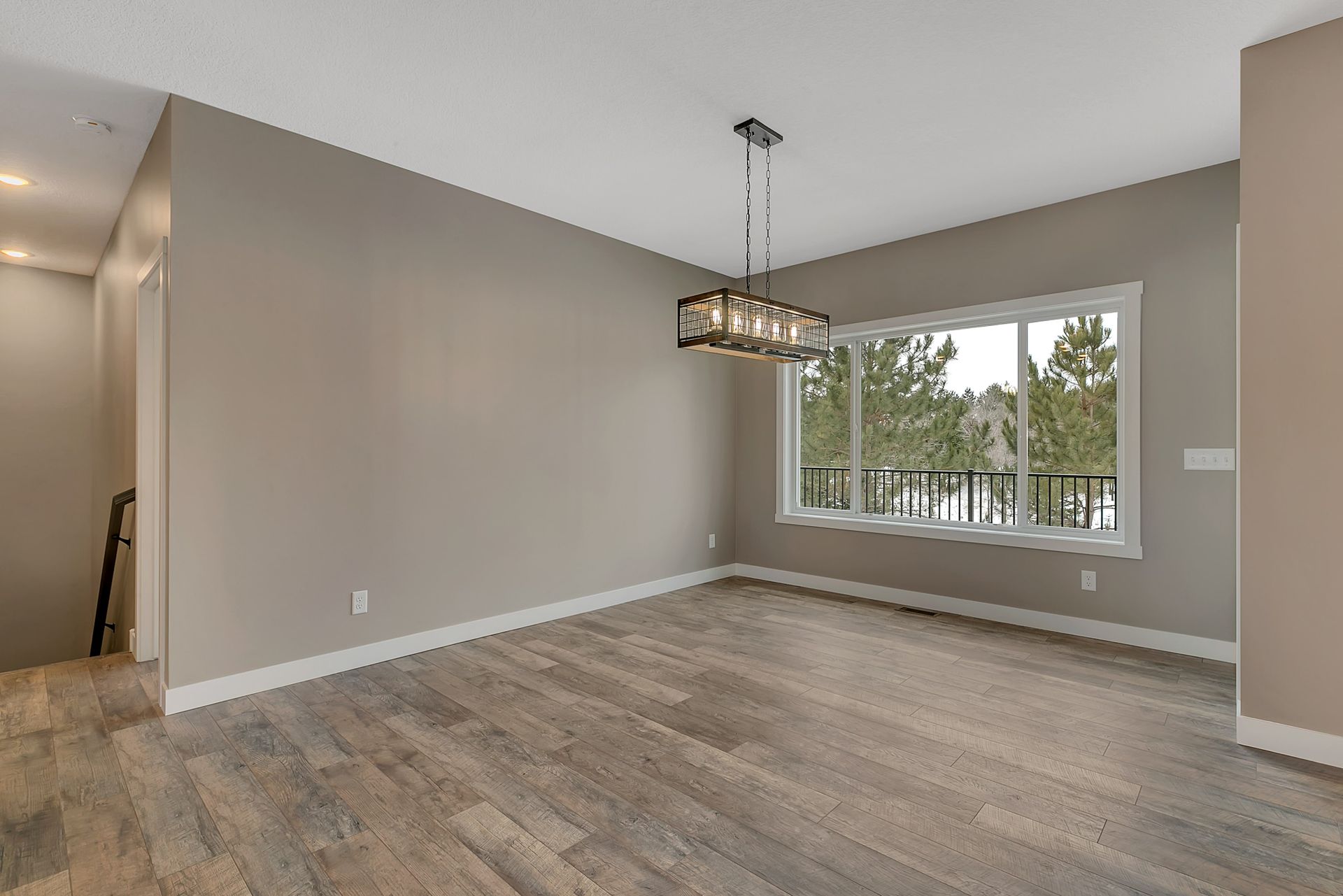 An empty living room with hardwood floors and a large window.