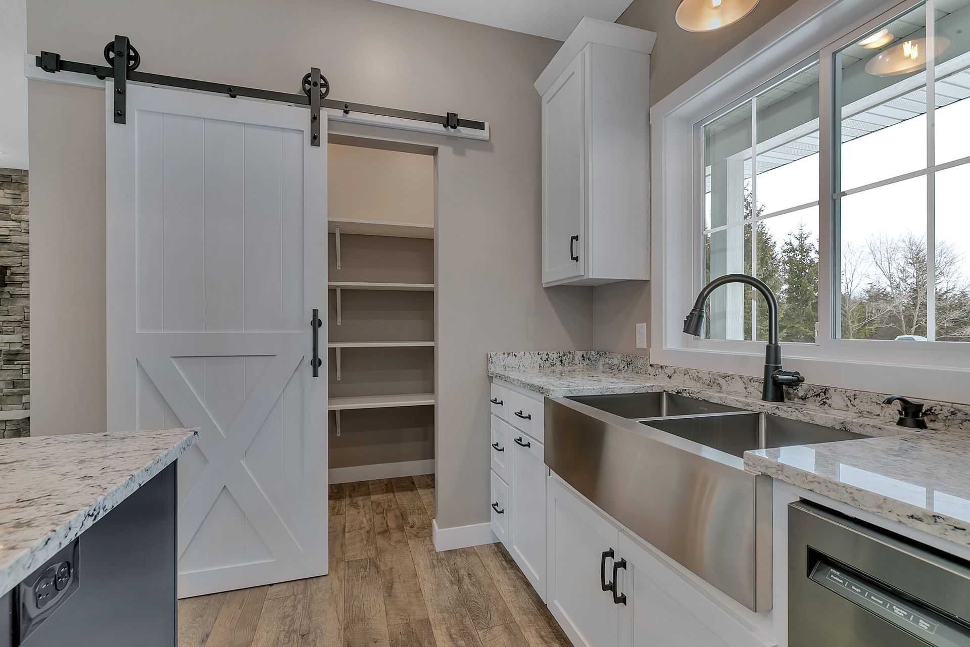 A kitchen with a sliding barn door leading to a pantry.