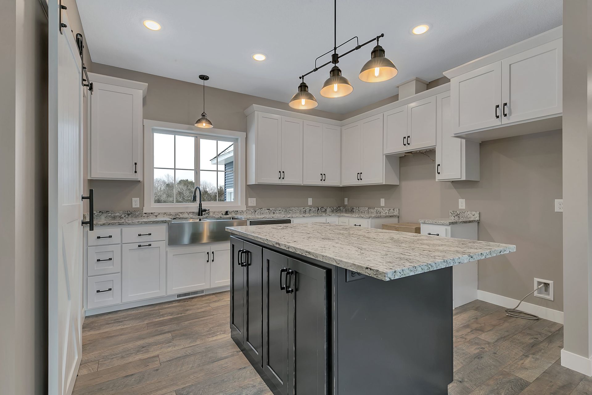 A kitchen with white cabinets , granite counter tops , and a large island.