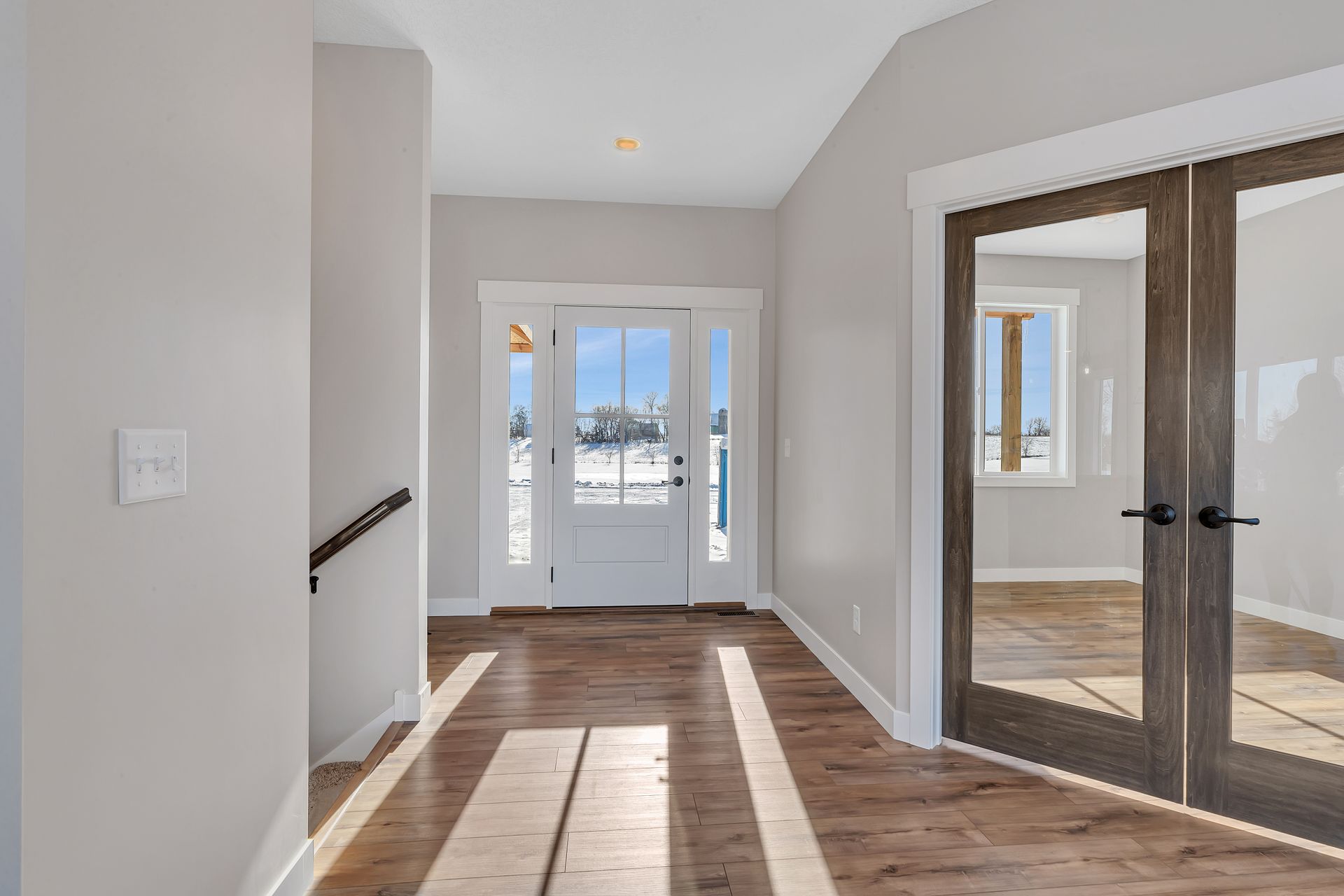 A hallway in a house with hardwood floors and a white door.