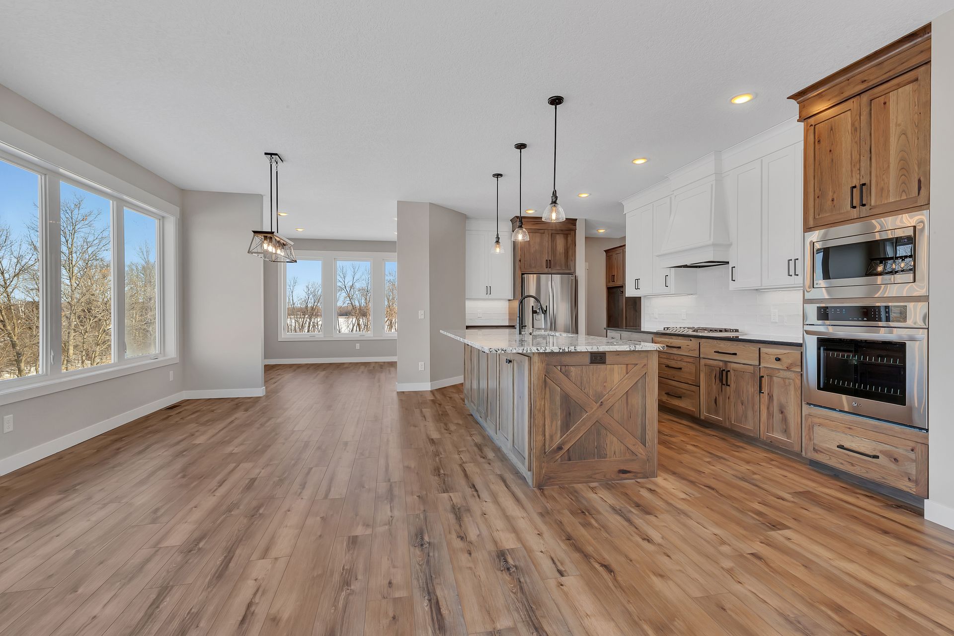 An empty kitchen with hardwood floors and stainless steel appliances.