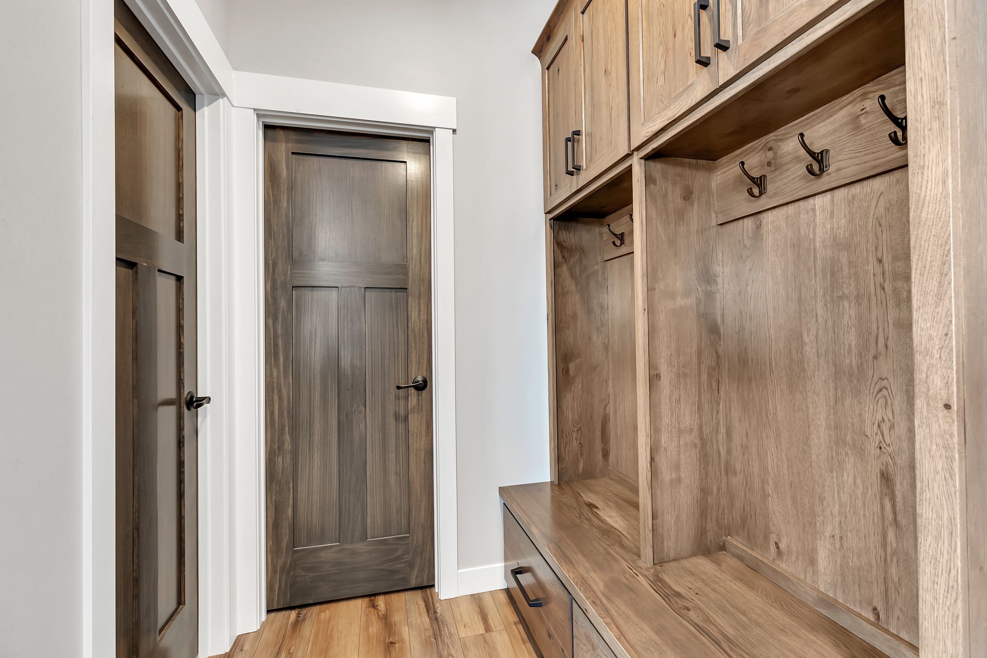 A hallway with wooden cabinets and hooks on the wall.