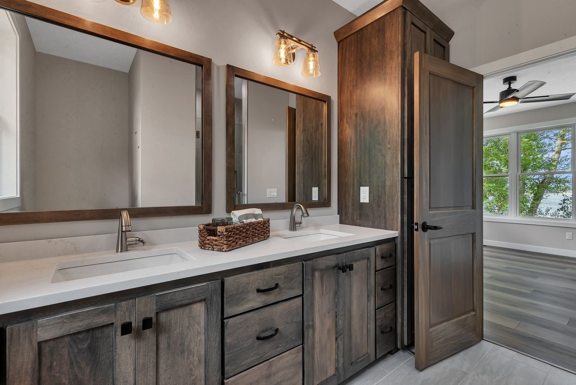 A bathroom with two sinks , two mirrors and a ceiling fan.