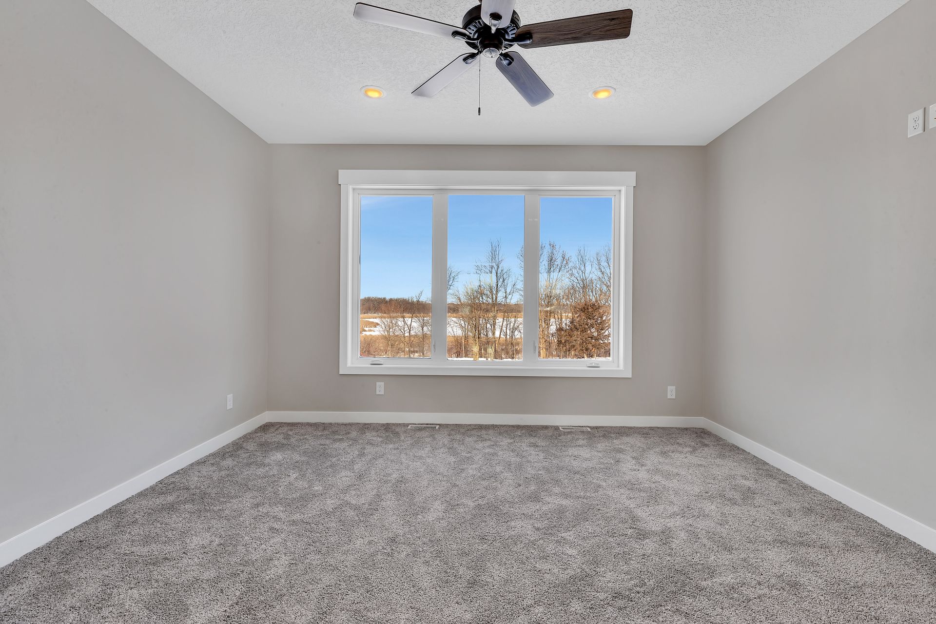 An empty room with a ceiling fan and a window.