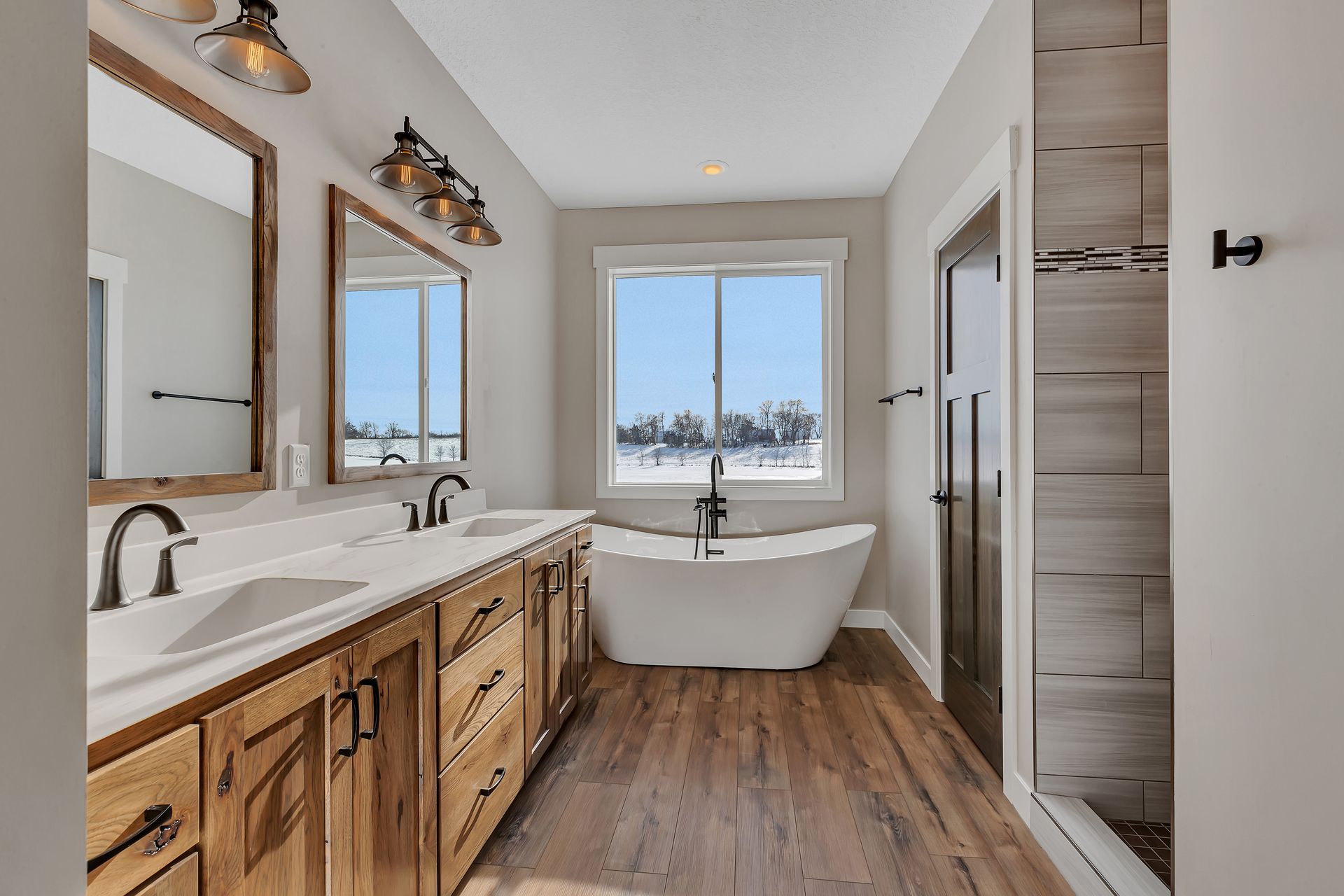 A bathroom with two sinks , a tub , and a window.