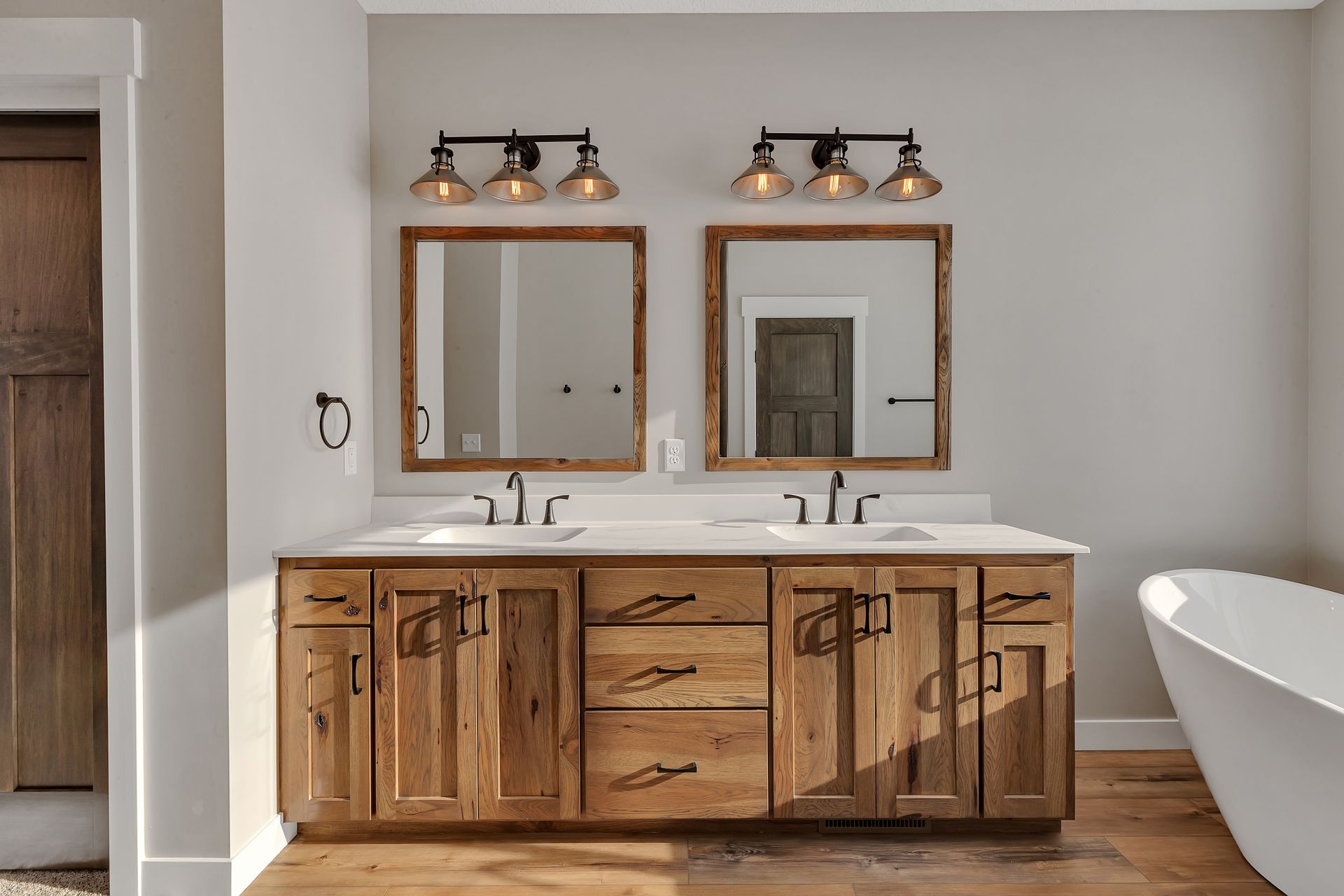 A bathroom with two sinks , two mirrors , and a bathtub.