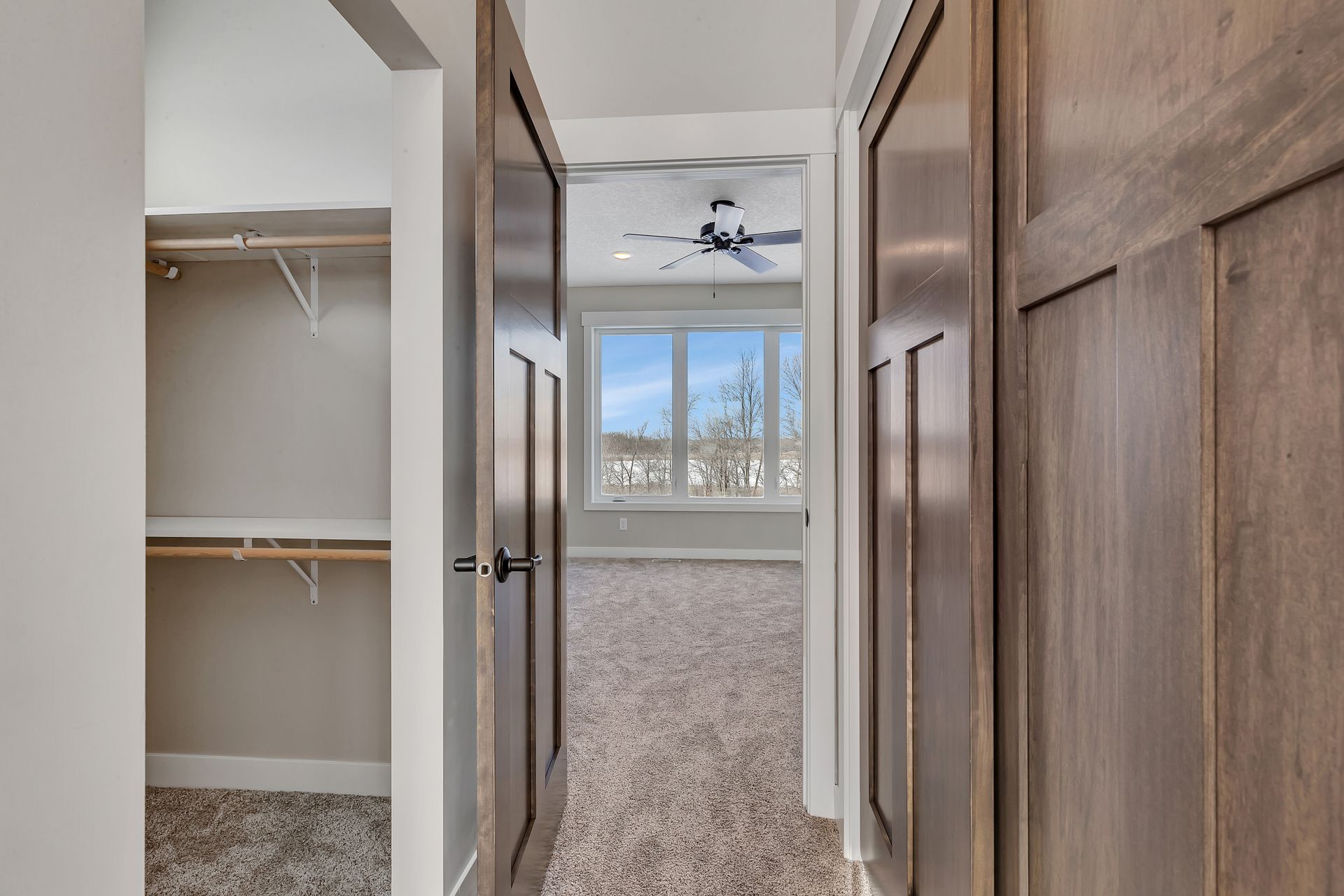 A hallway leading to a bedroom with a ceiling fan.