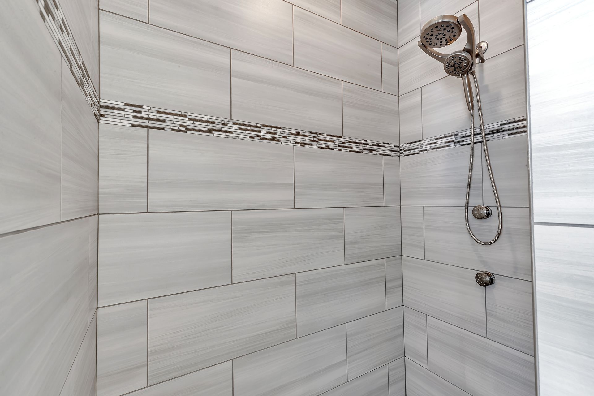 A shower with white tiles and a shower head.