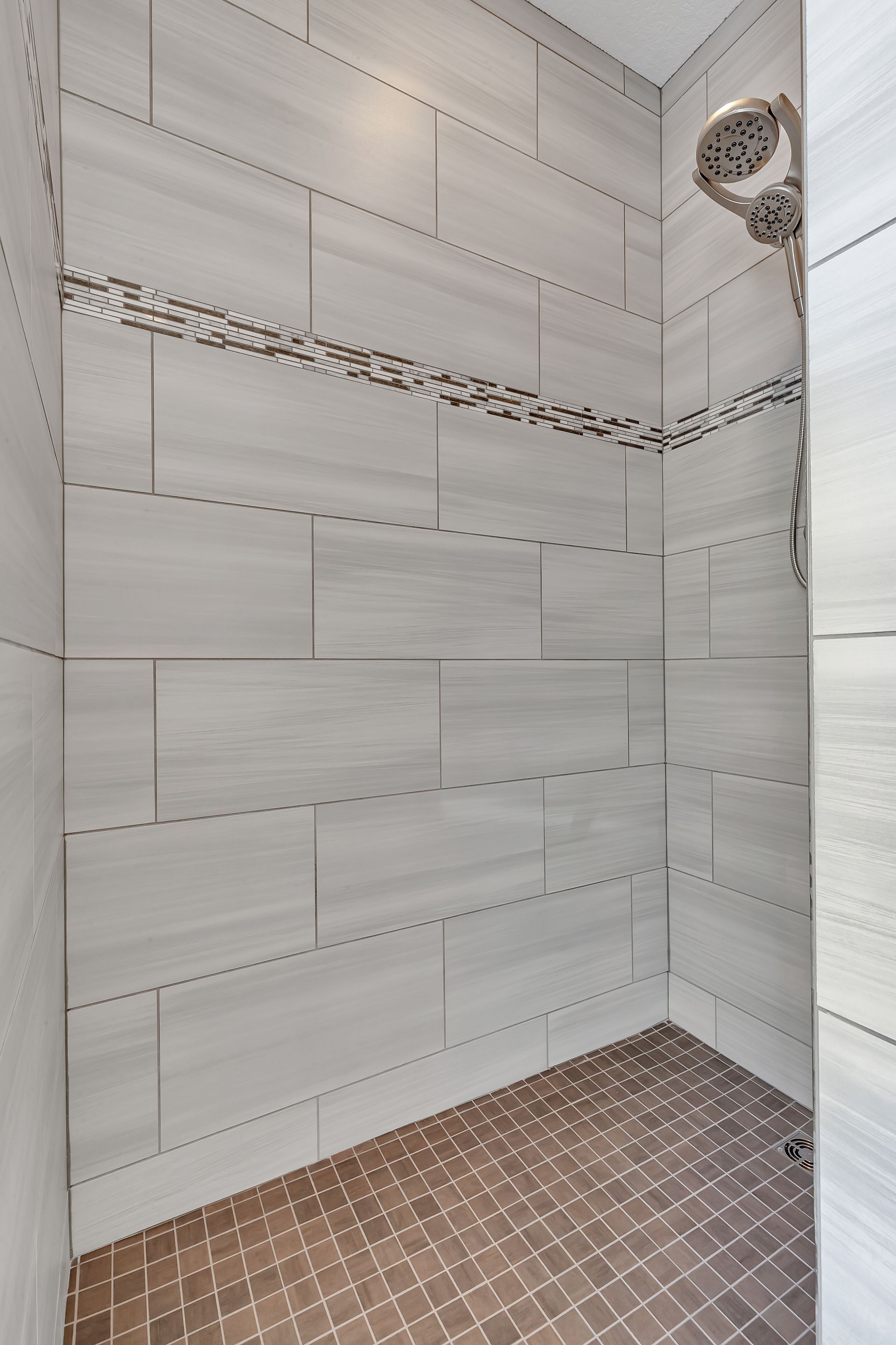 A walk in shower with tiled walls and a mosaic floor.