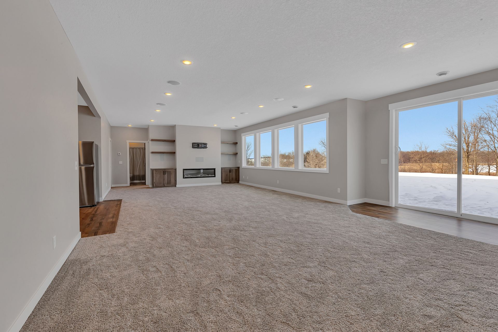 A large empty living room with a fireplace and sliding glass doors.