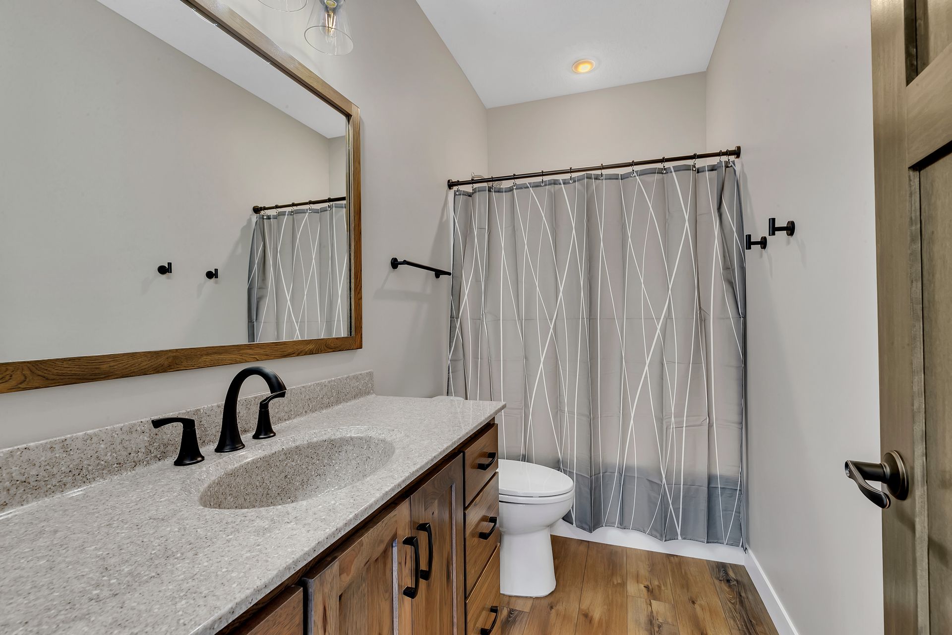 A bathroom with a toilet , sink , mirror and shower curtain.