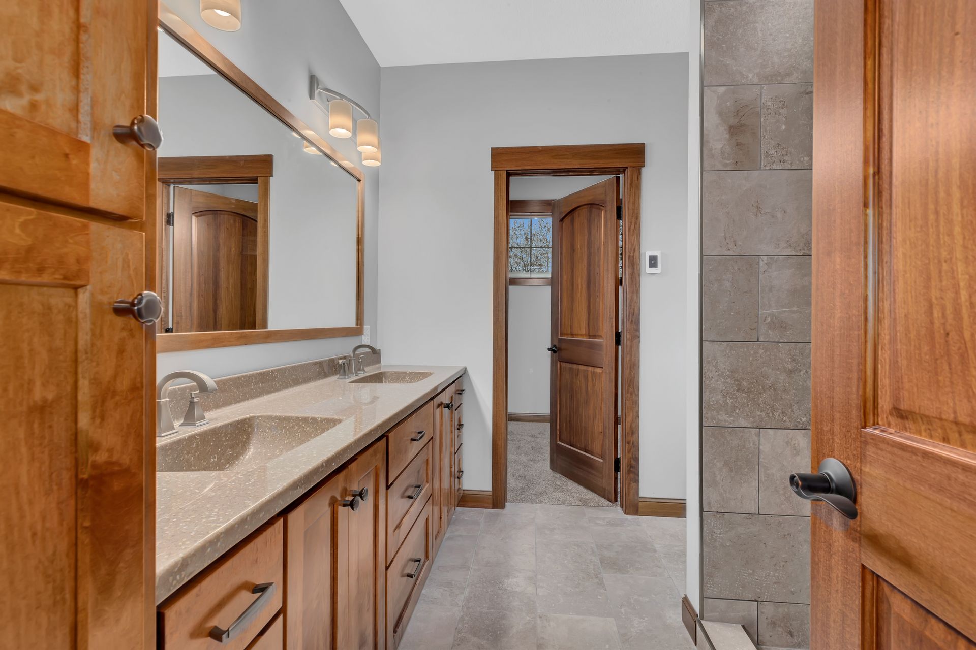 A bathroom with two sinks , a mirror and a walk in shower.