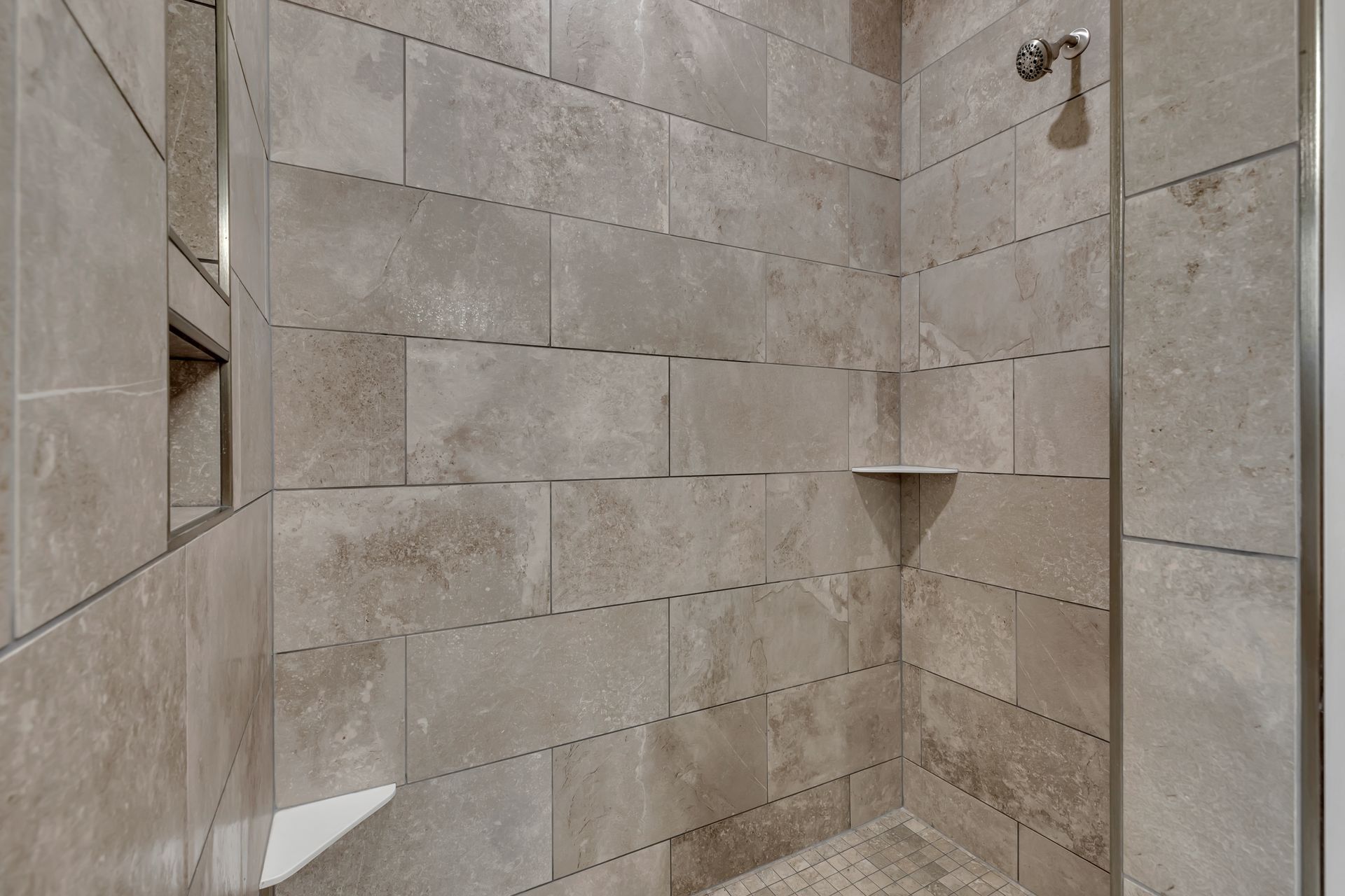 A walk in shower with tiled walls and a glass door.