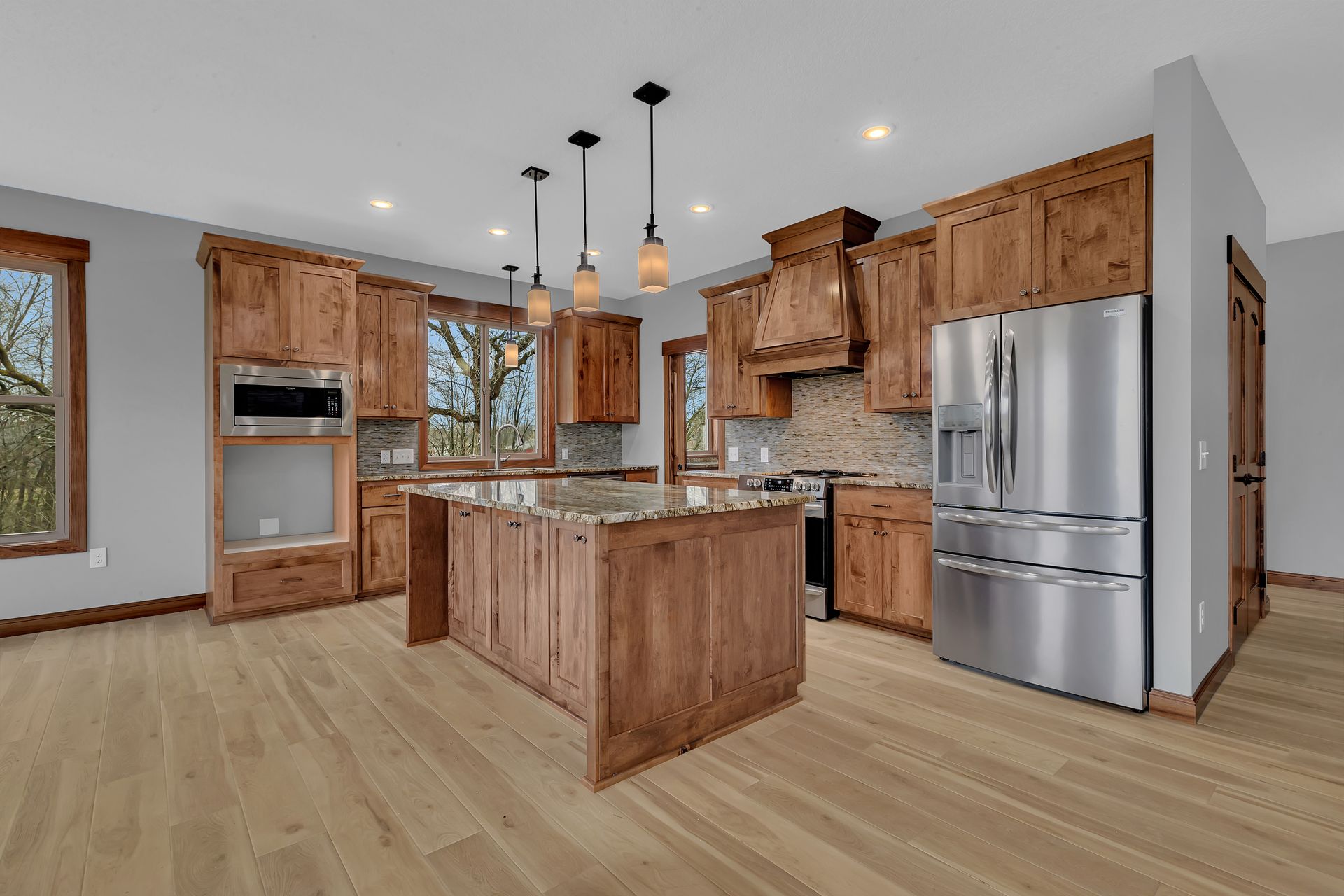 A kitchen with wooden cabinets , stainless steel appliances , and a large island.