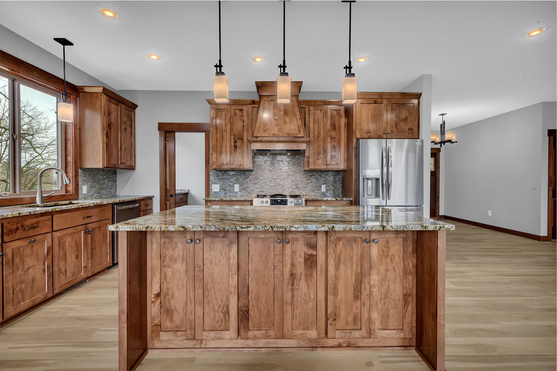 A kitchen with wooden cabinets , granite counter tops , and a large island.