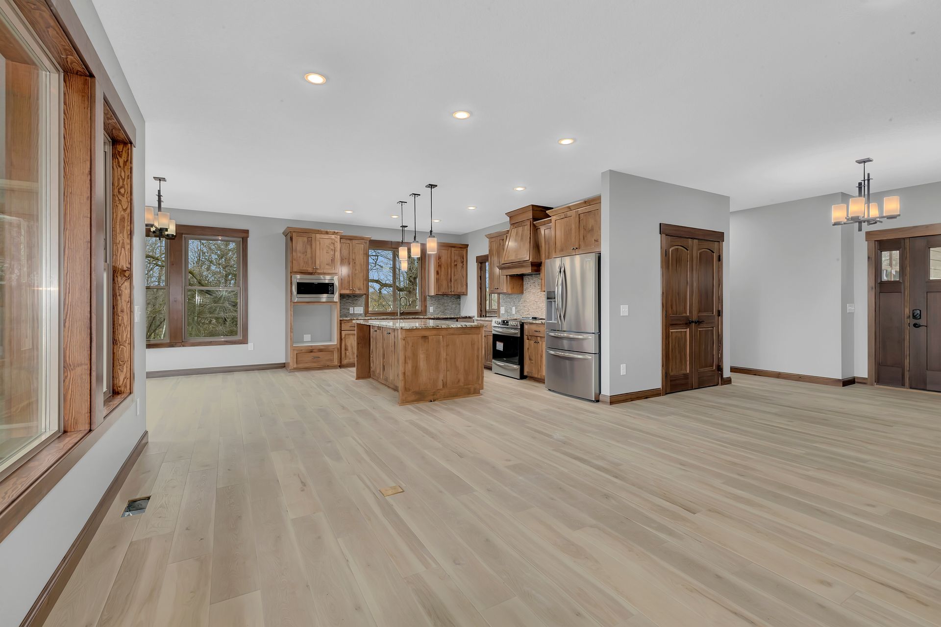 A large empty room with hardwood floors and a kitchen.