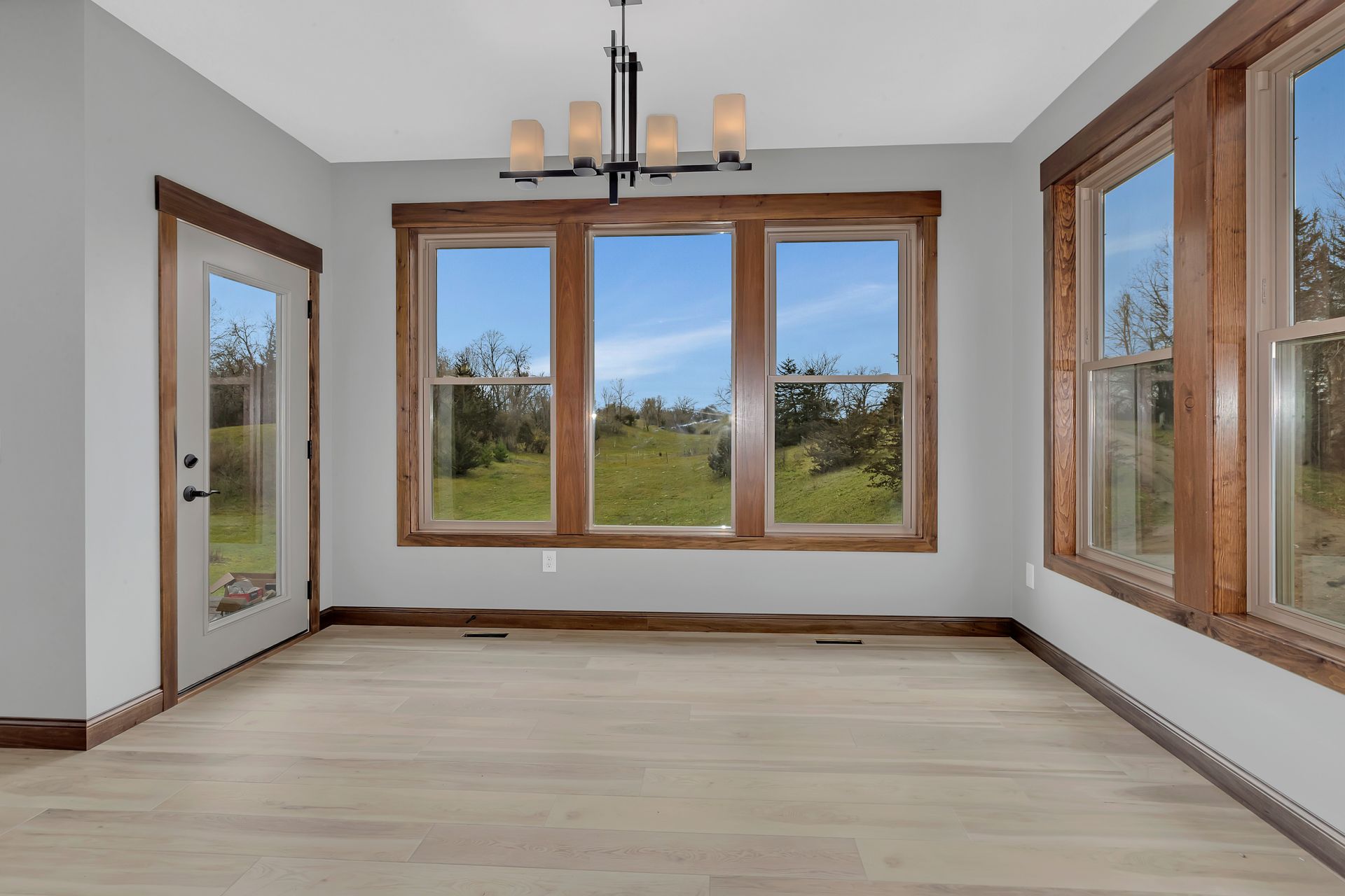 An empty room with a lot of windows and a chandelier.