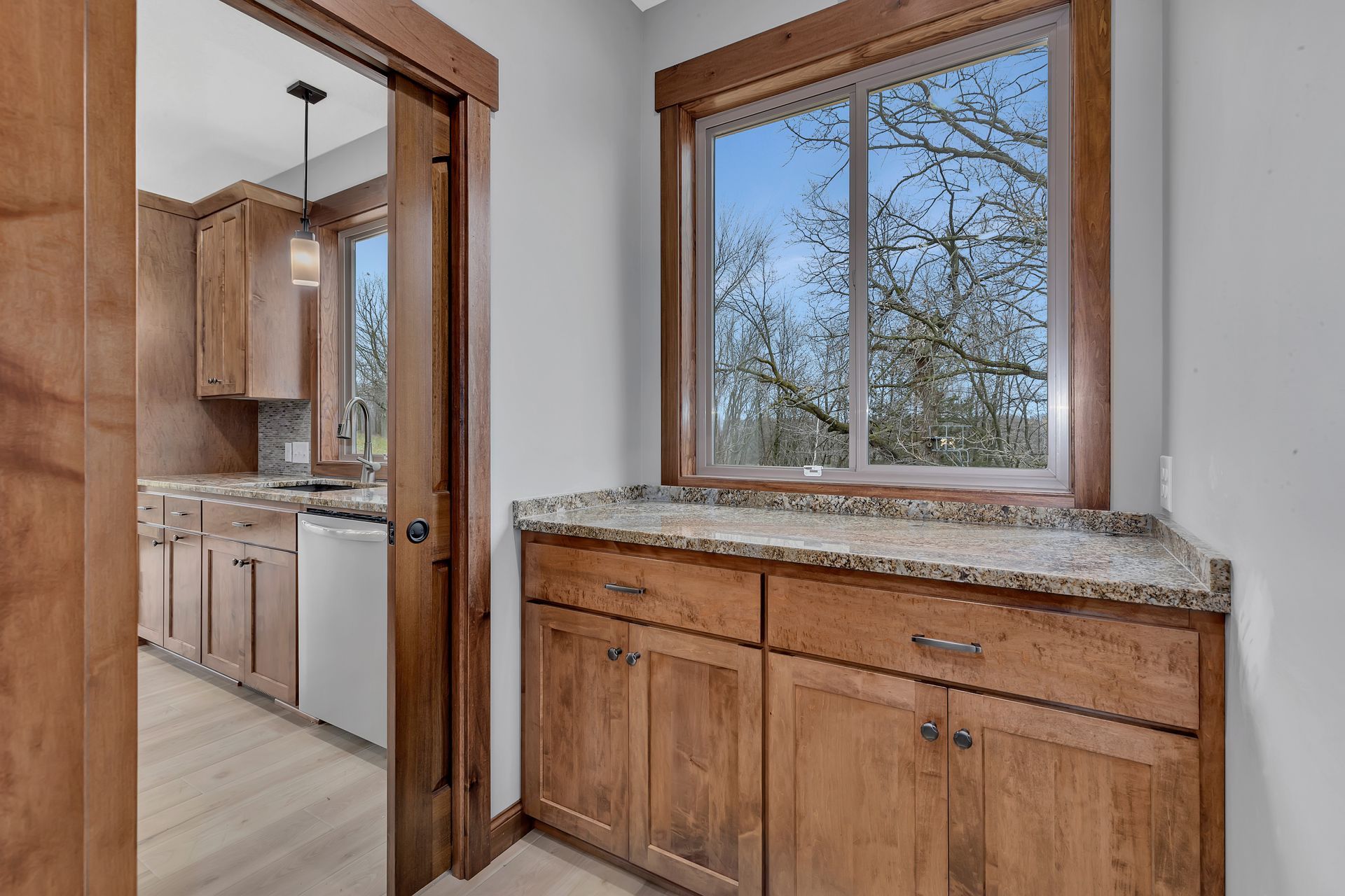 A kitchen with wooden cabinets , granite counter tops and a large window.