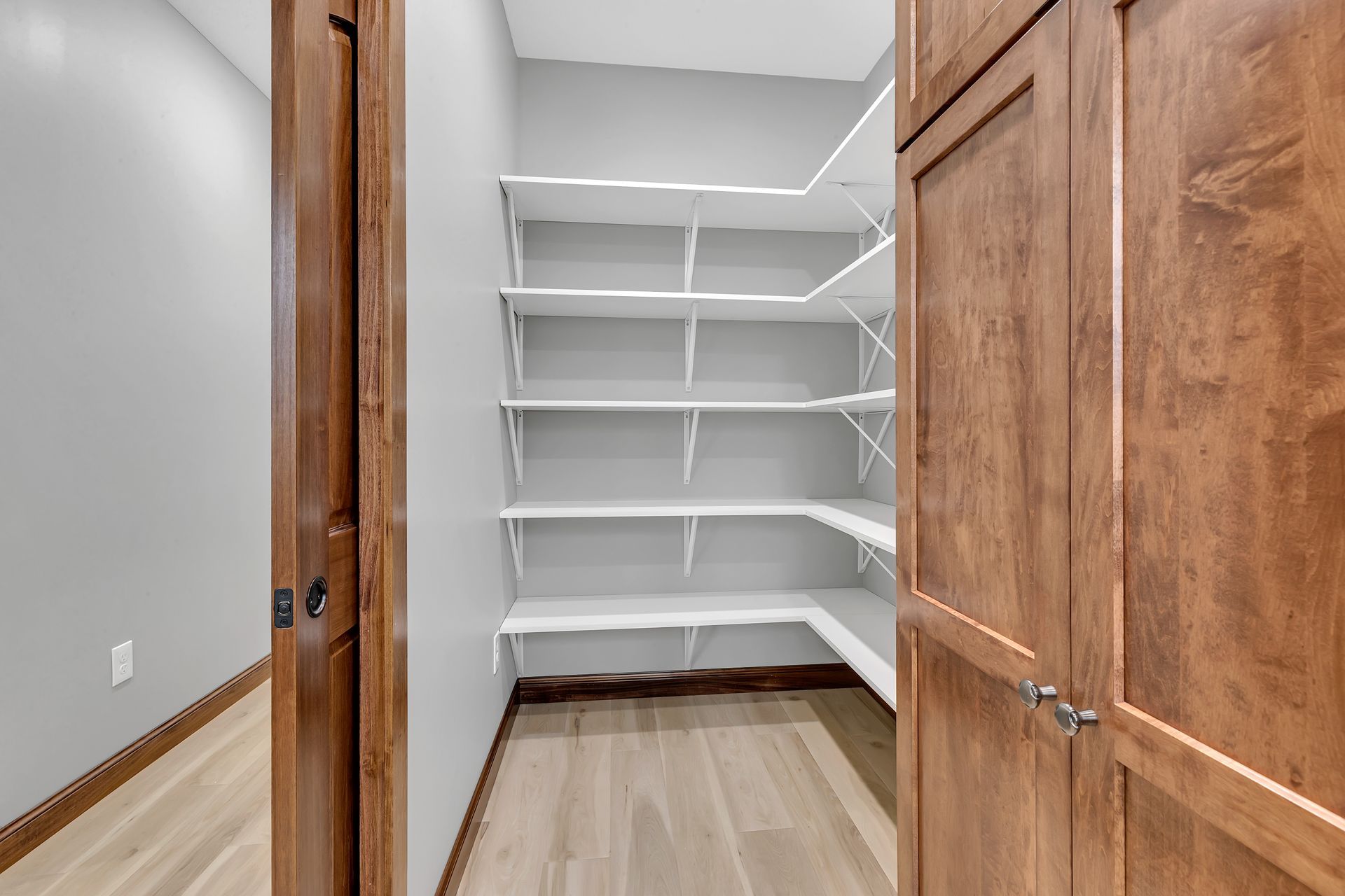A walk in closet with shelves and a wooden door.