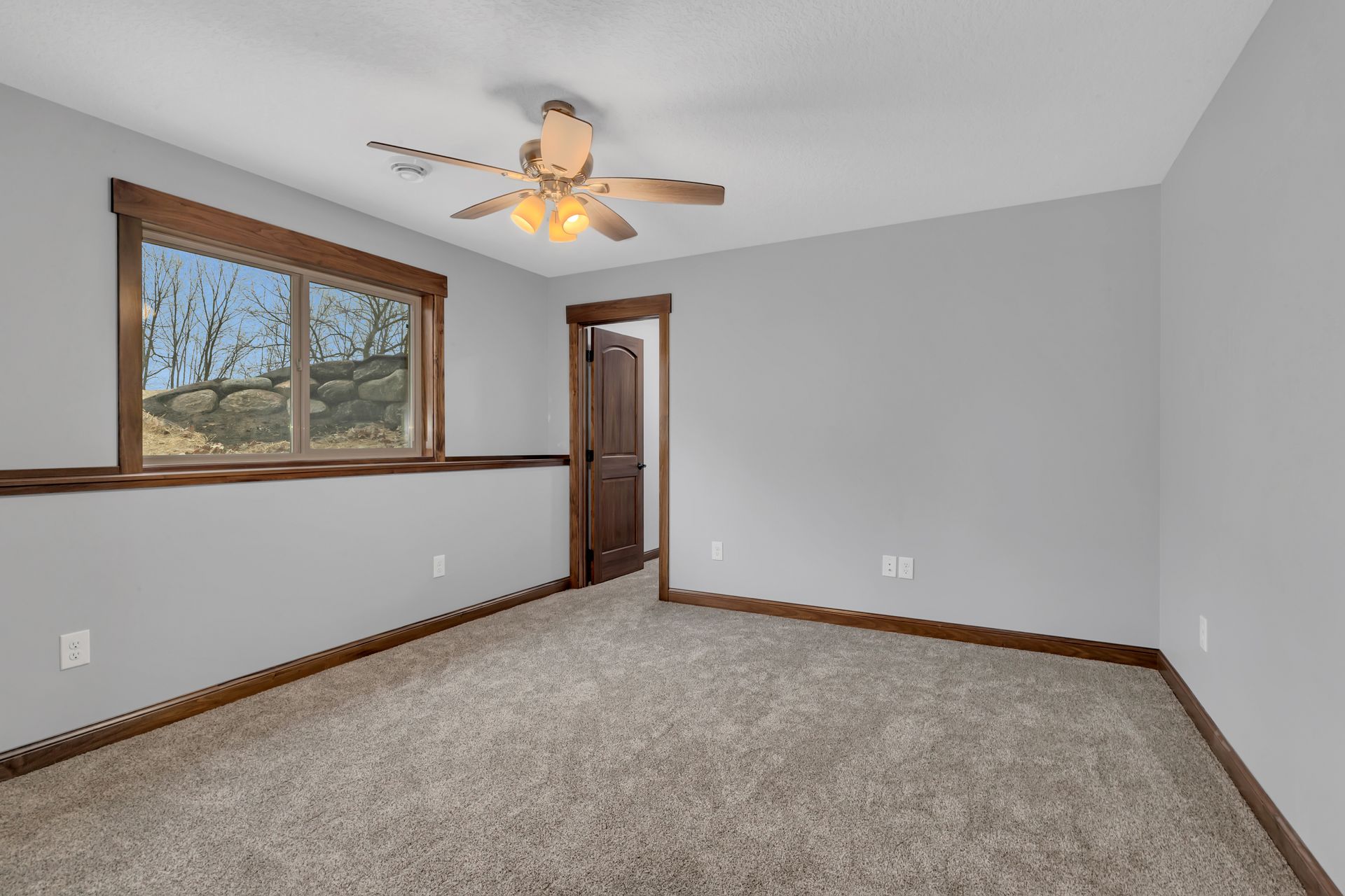 An empty bedroom with a ceiling fan and a window.