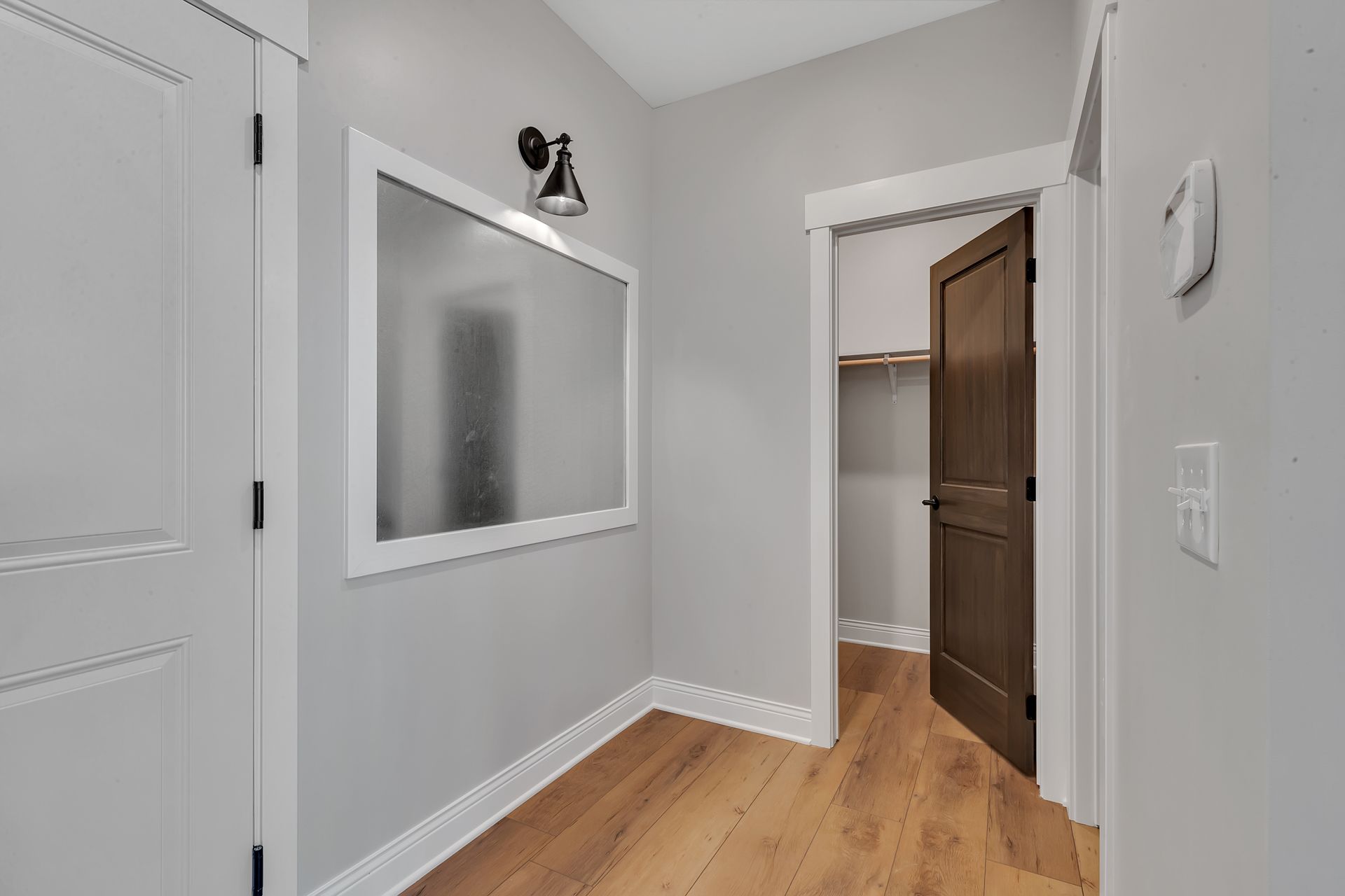 A hallway with hardwood floors and a large mirror on the wall.