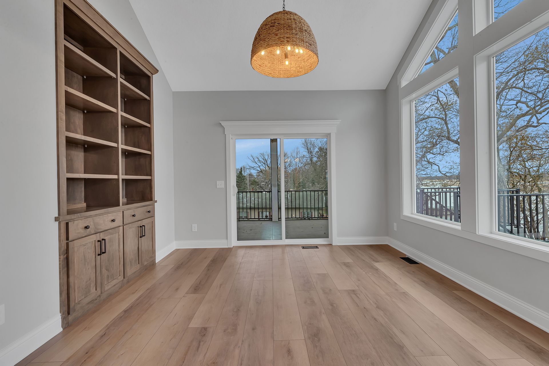 An empty living room with hardwood floors and a sliding glass door.