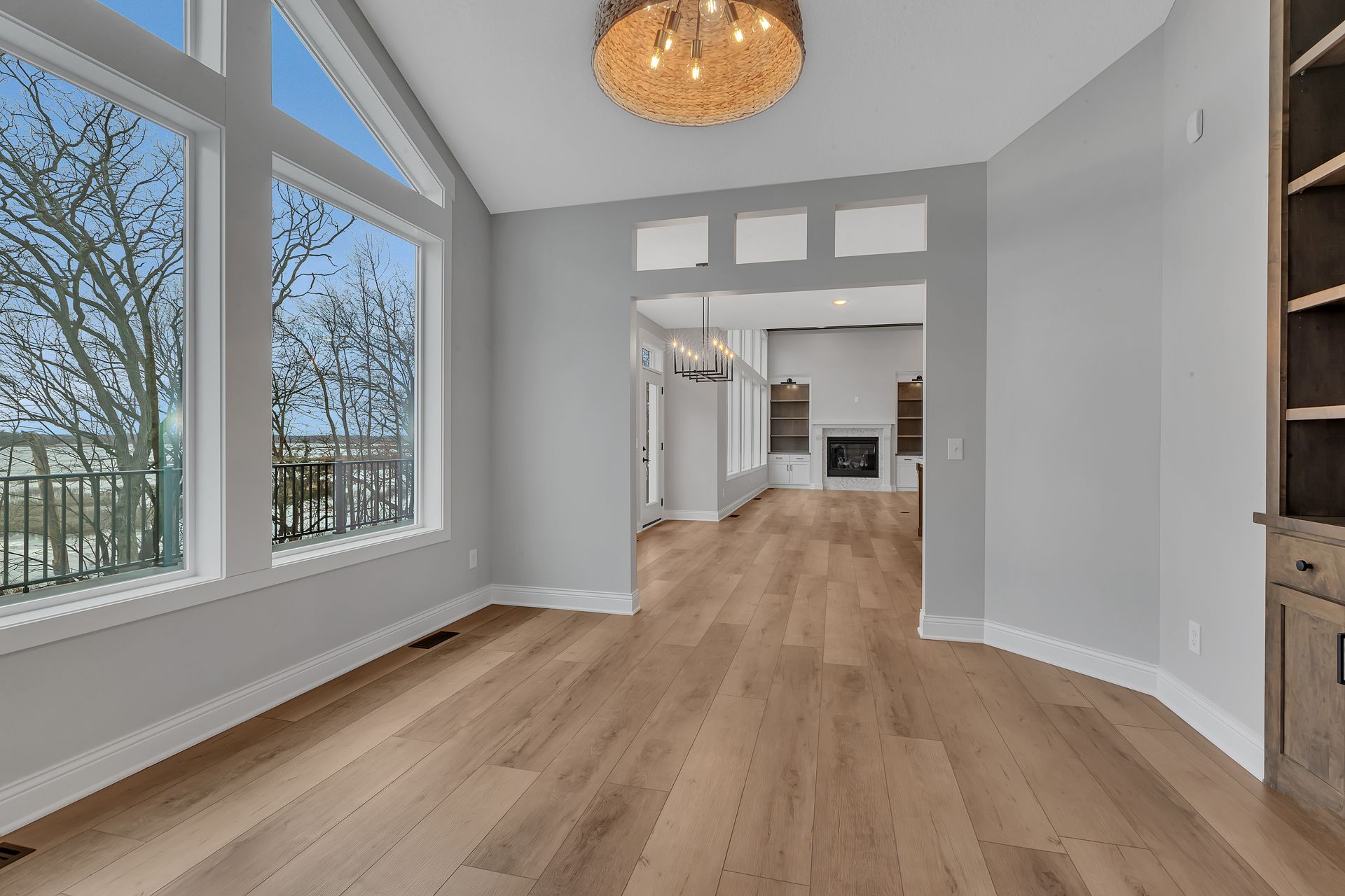 An empty living room with hardwood floors and a chandelier.
