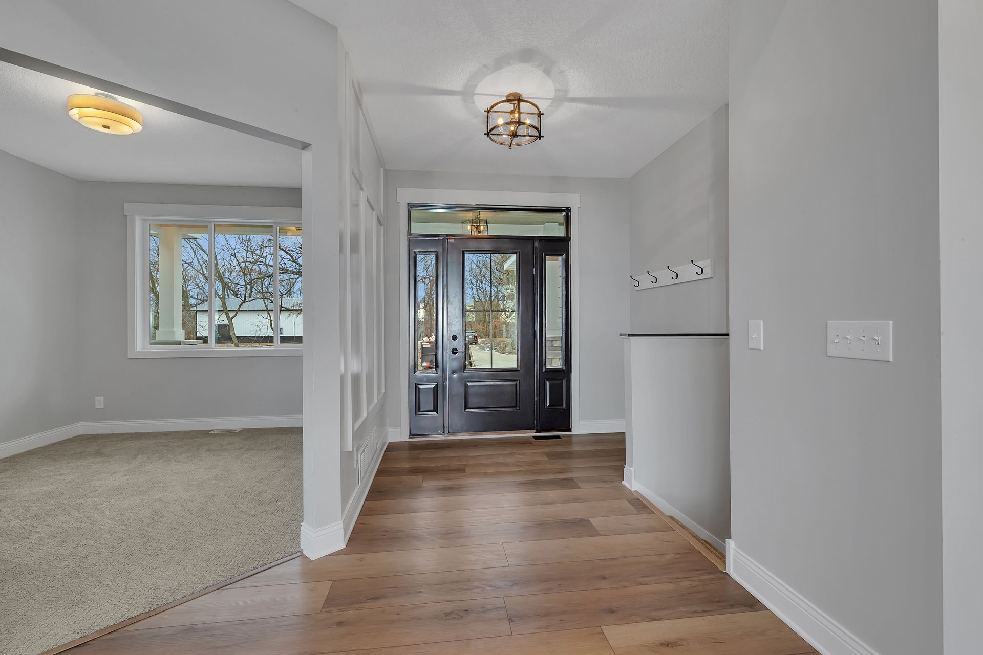 A hallway in a house with hardwood floors and a black door.