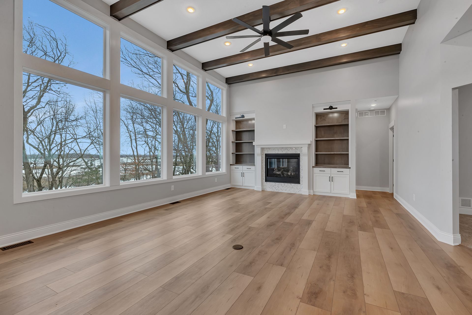 An empty living room with hardwood floors and a fireplace.