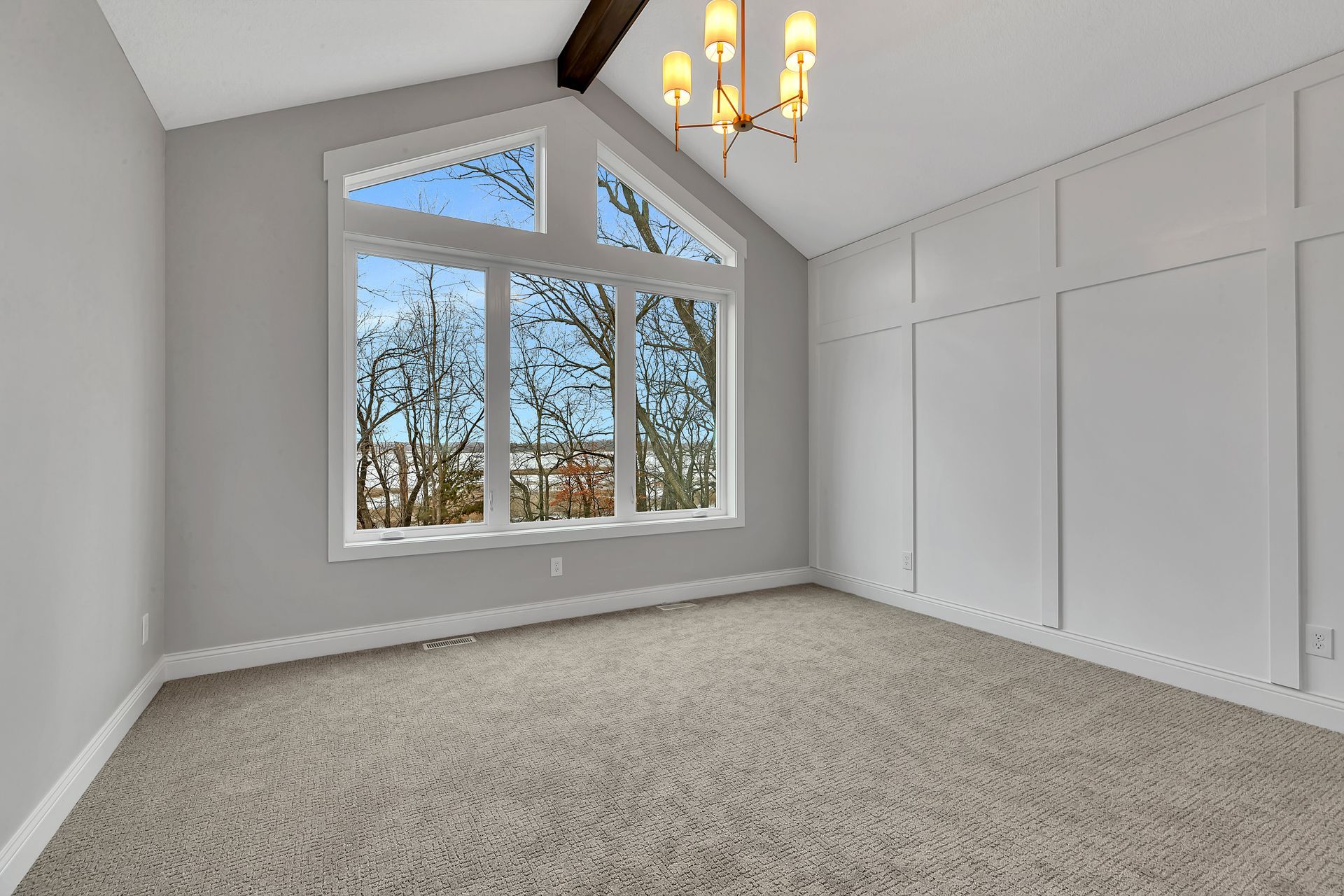 An empty room with a large window and a chandelier.