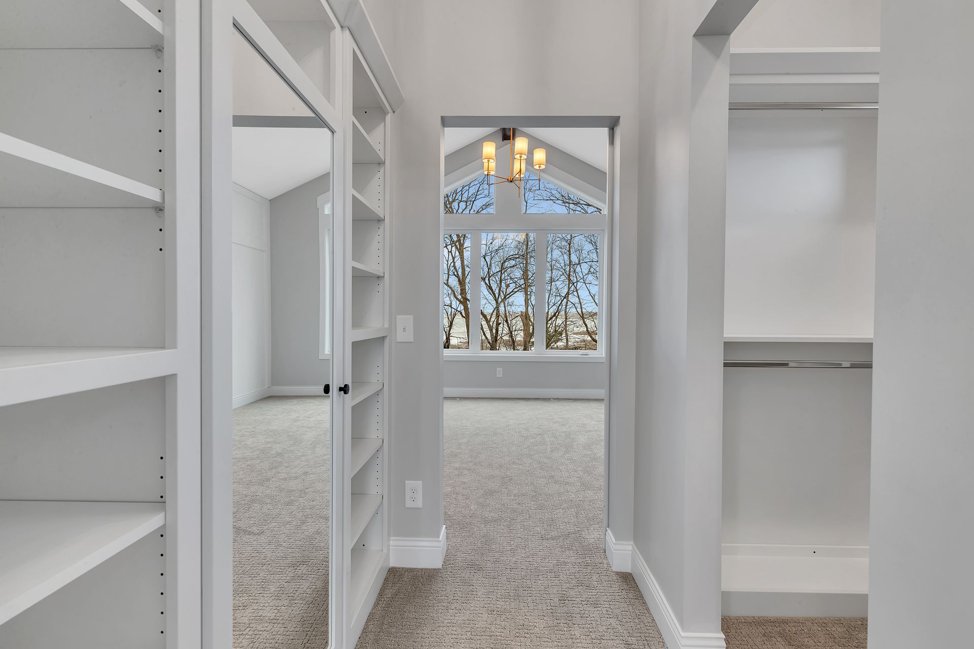 A walk in closet with lots of shelves and a large window.