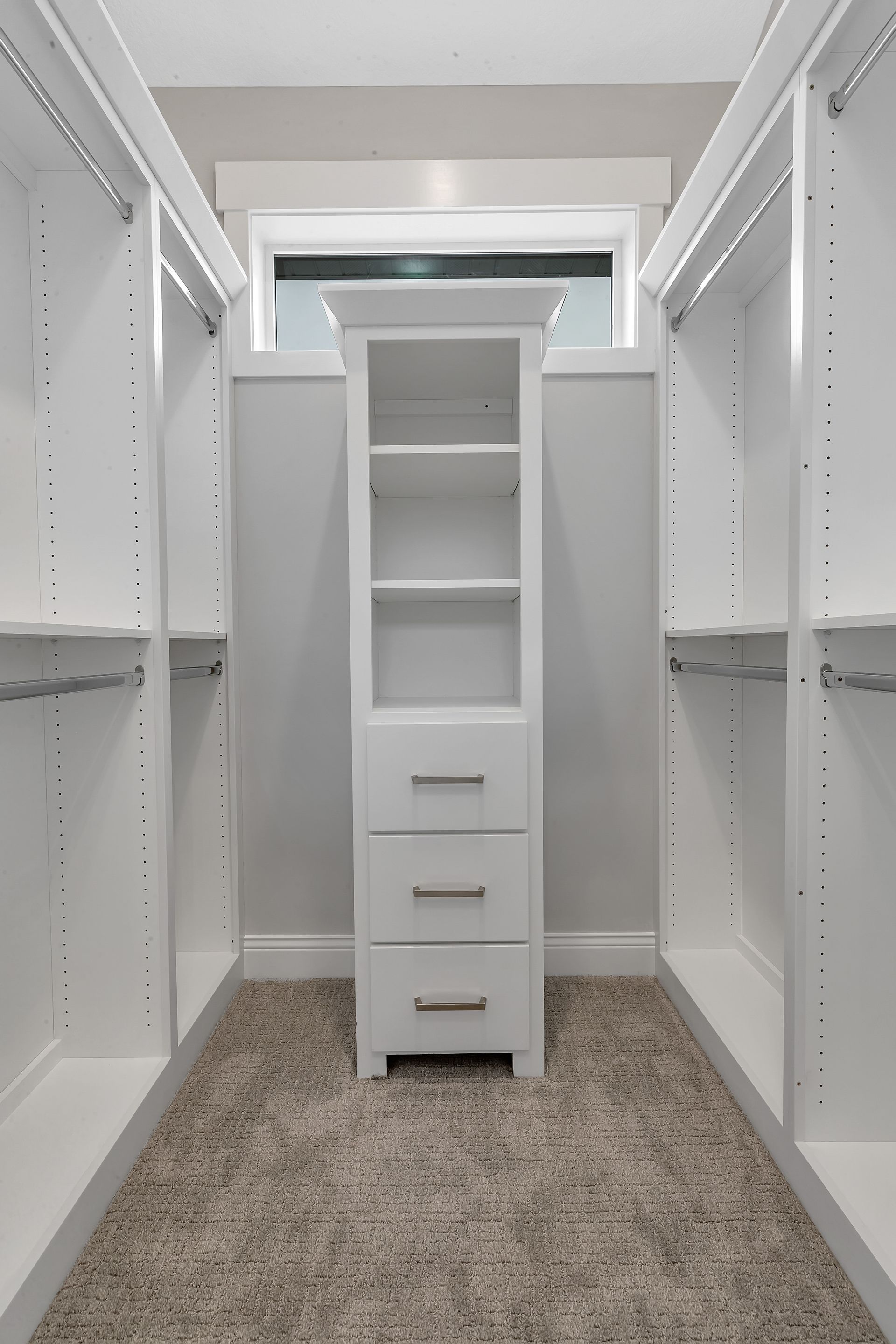 An empty walk in closet with white shelves and drawers.