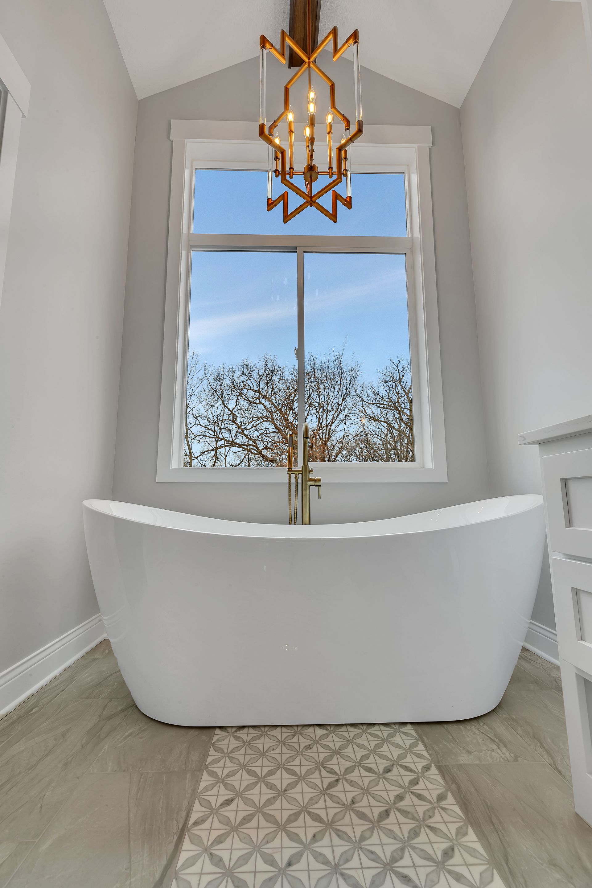 A bathroom with a bathtub and a chandelier hanging from the ceiling.