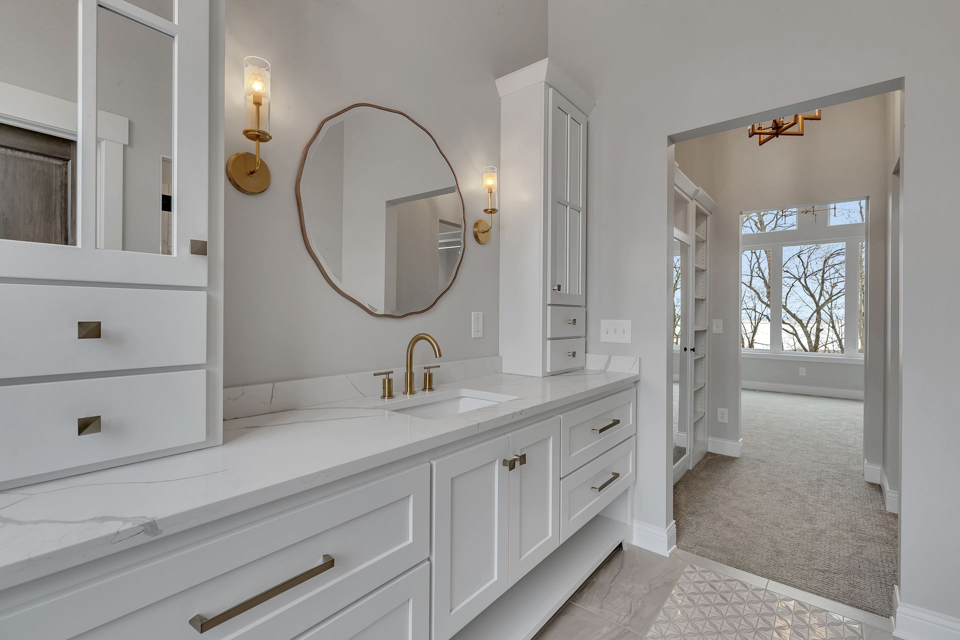 A bathroom with white cabinets , a sink , a mirror and a walk in closet.