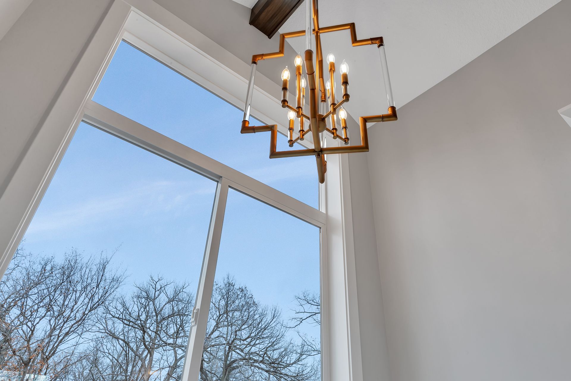 A chandelier is hanging from the ceiling in front of a large window.