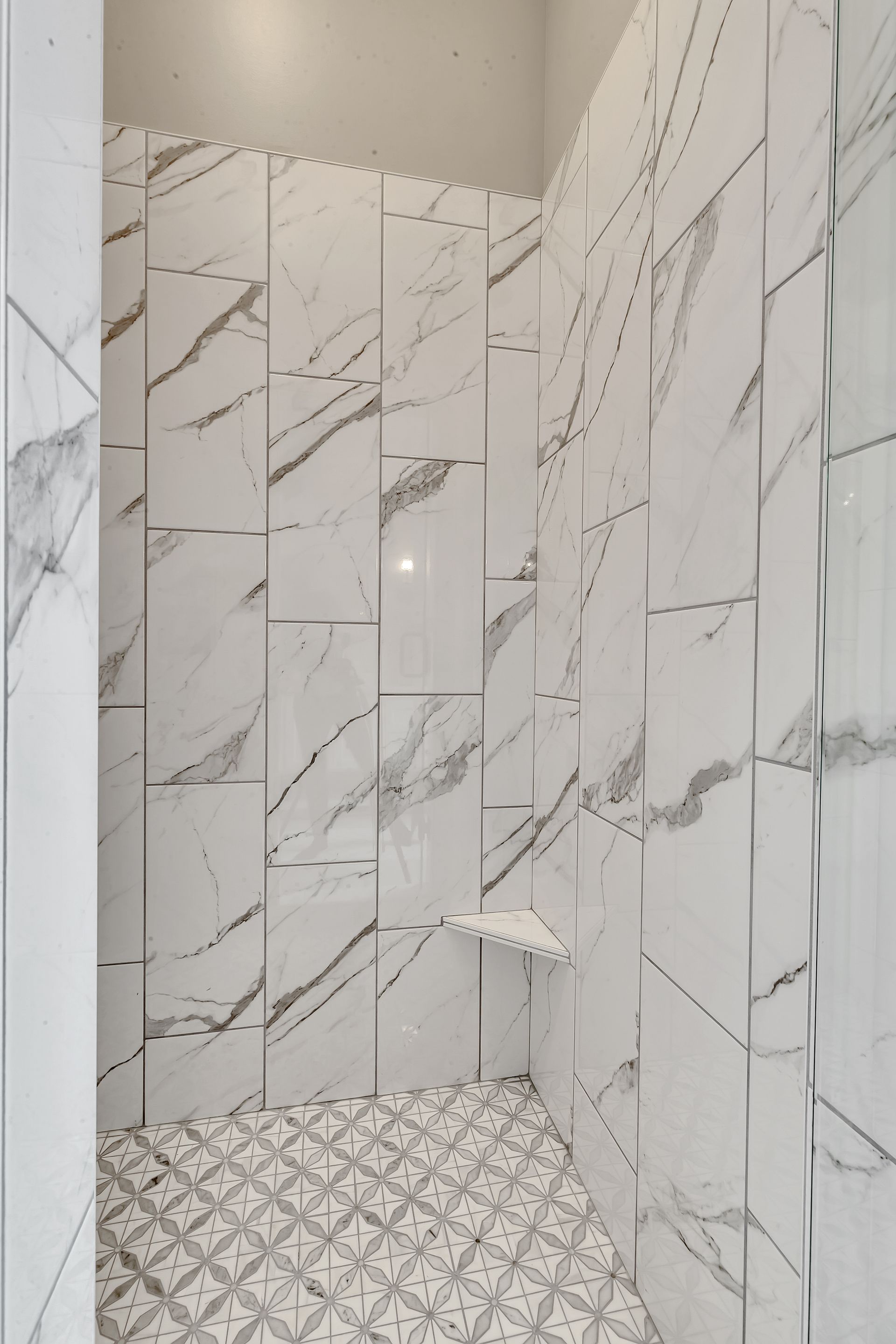 A bathroom with marble tiles and a walk in shower.