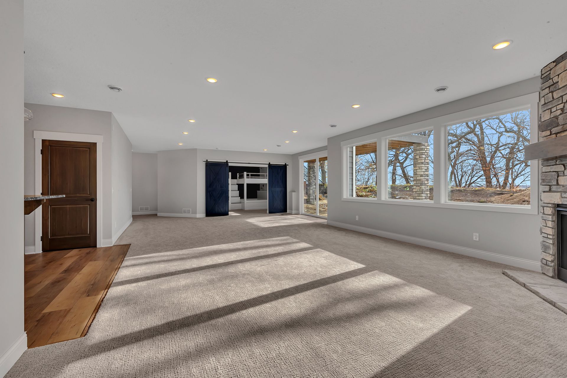 An empty living room with a lot of windows and a fireplace.