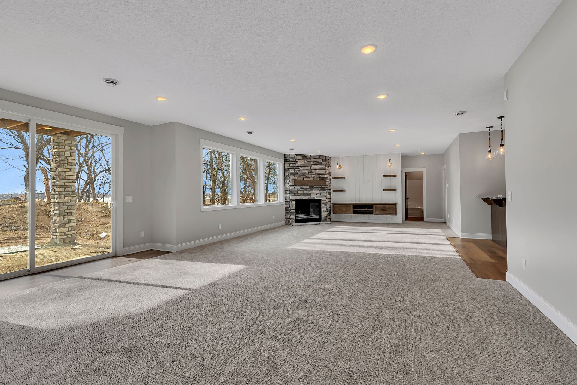 A large empty room with a fireplace and sliding glass doors.