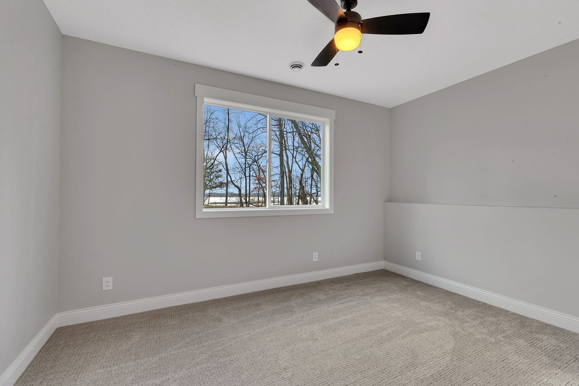 An empty bedroom with a ceiling fan and a window.