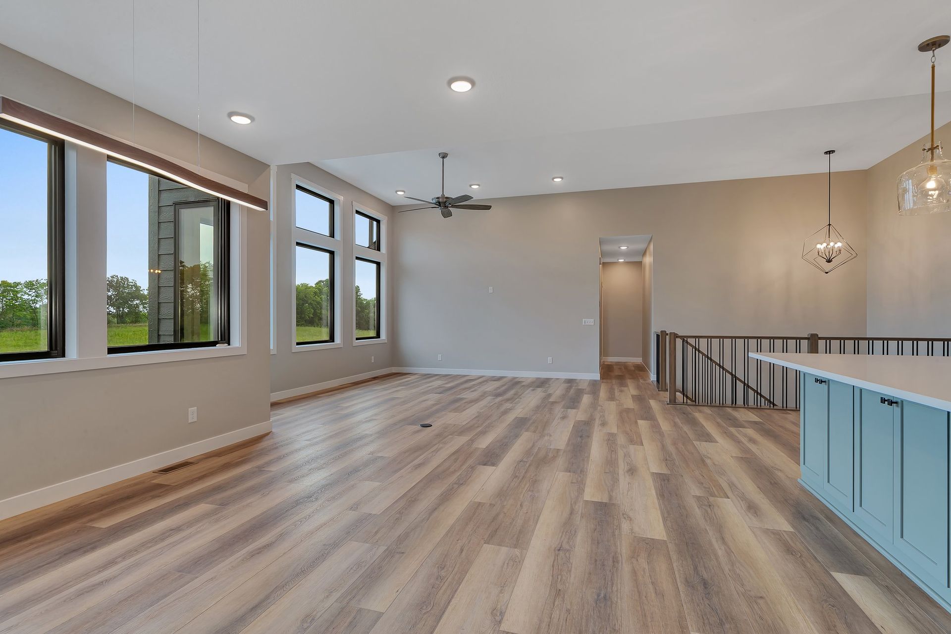 A large empty room with hardwood floors and a ceiling fan.