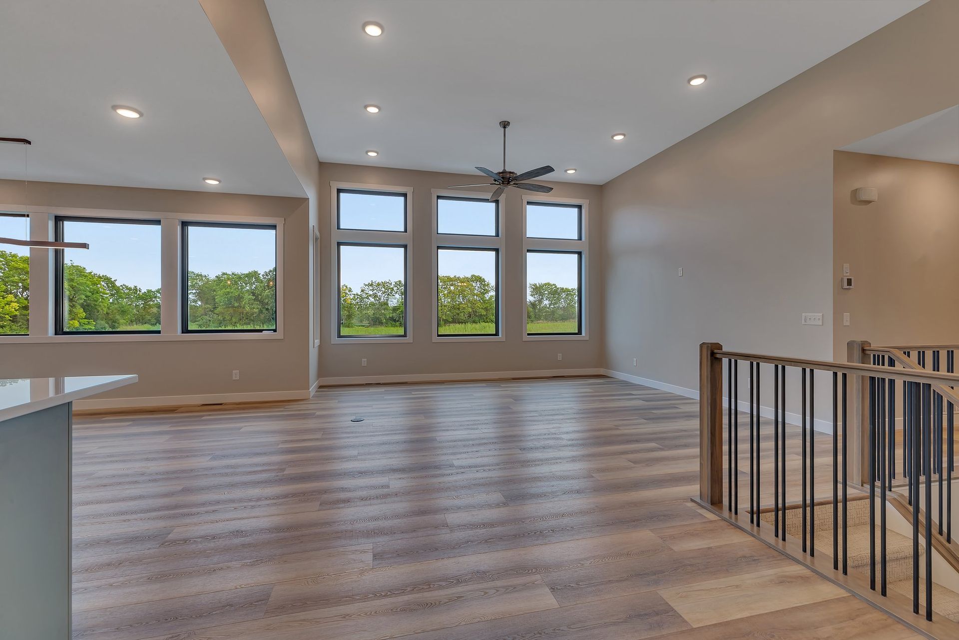 An empty living room with hardwood floors and a ceiling fan
