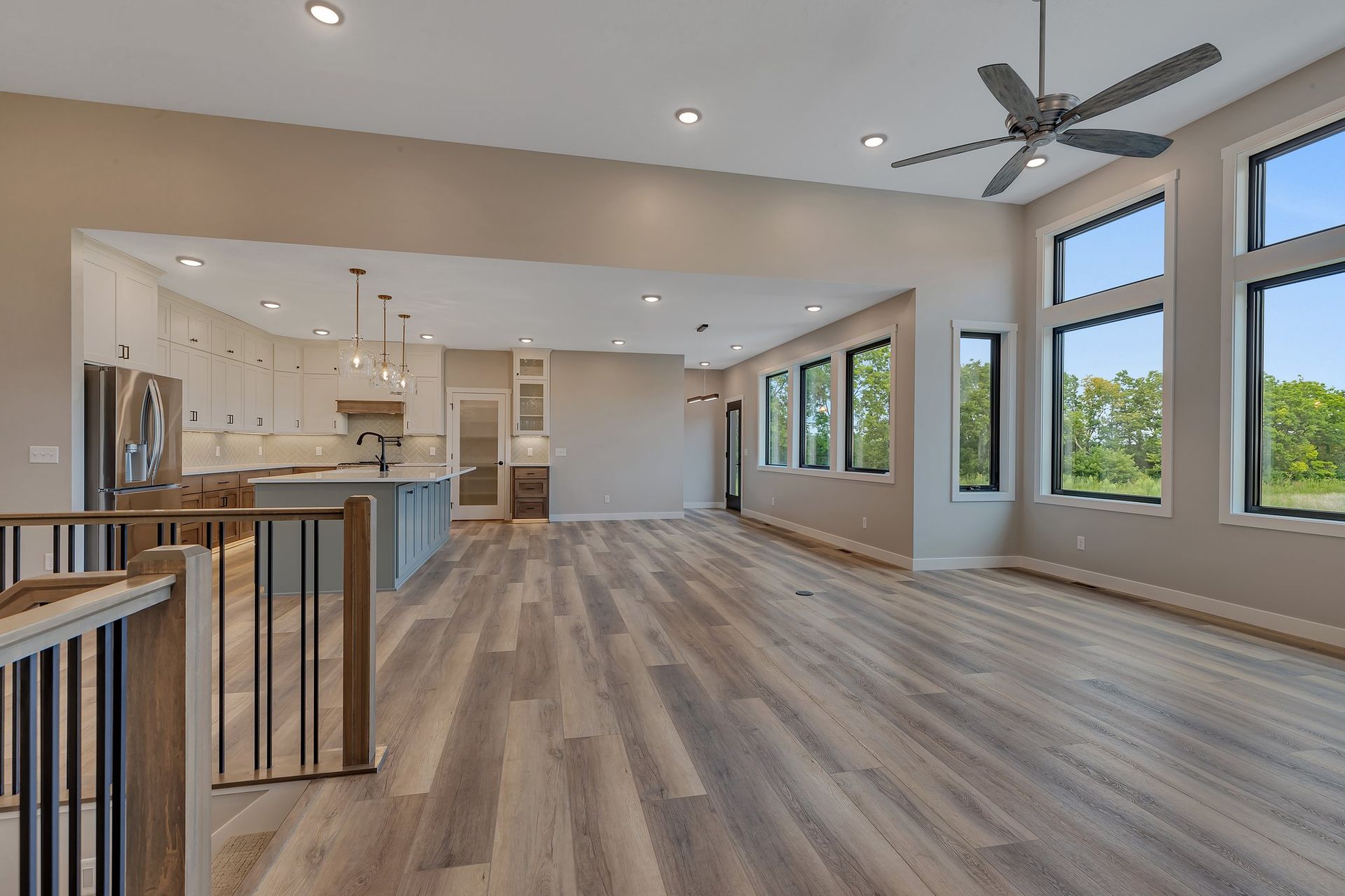 A large empty room with hardwood floors and a ceiling fan.