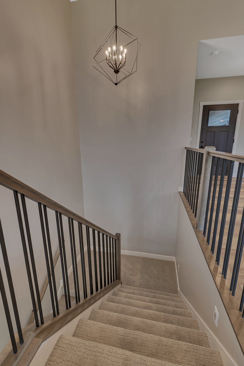 A staircase in a house with a chandelier hanging from the ceiling.