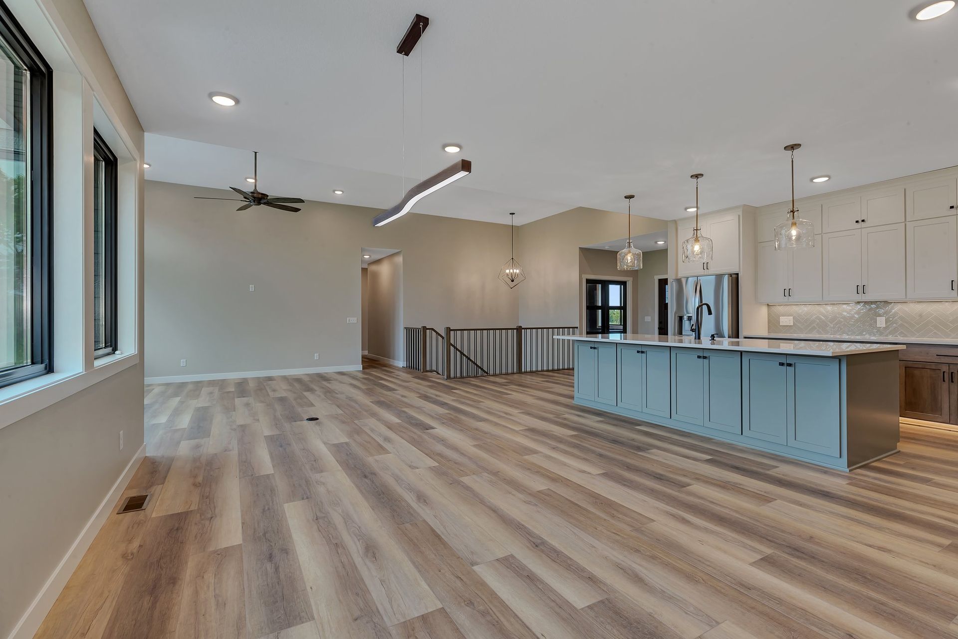 A large empty room with hardwood floors and a kitchen.