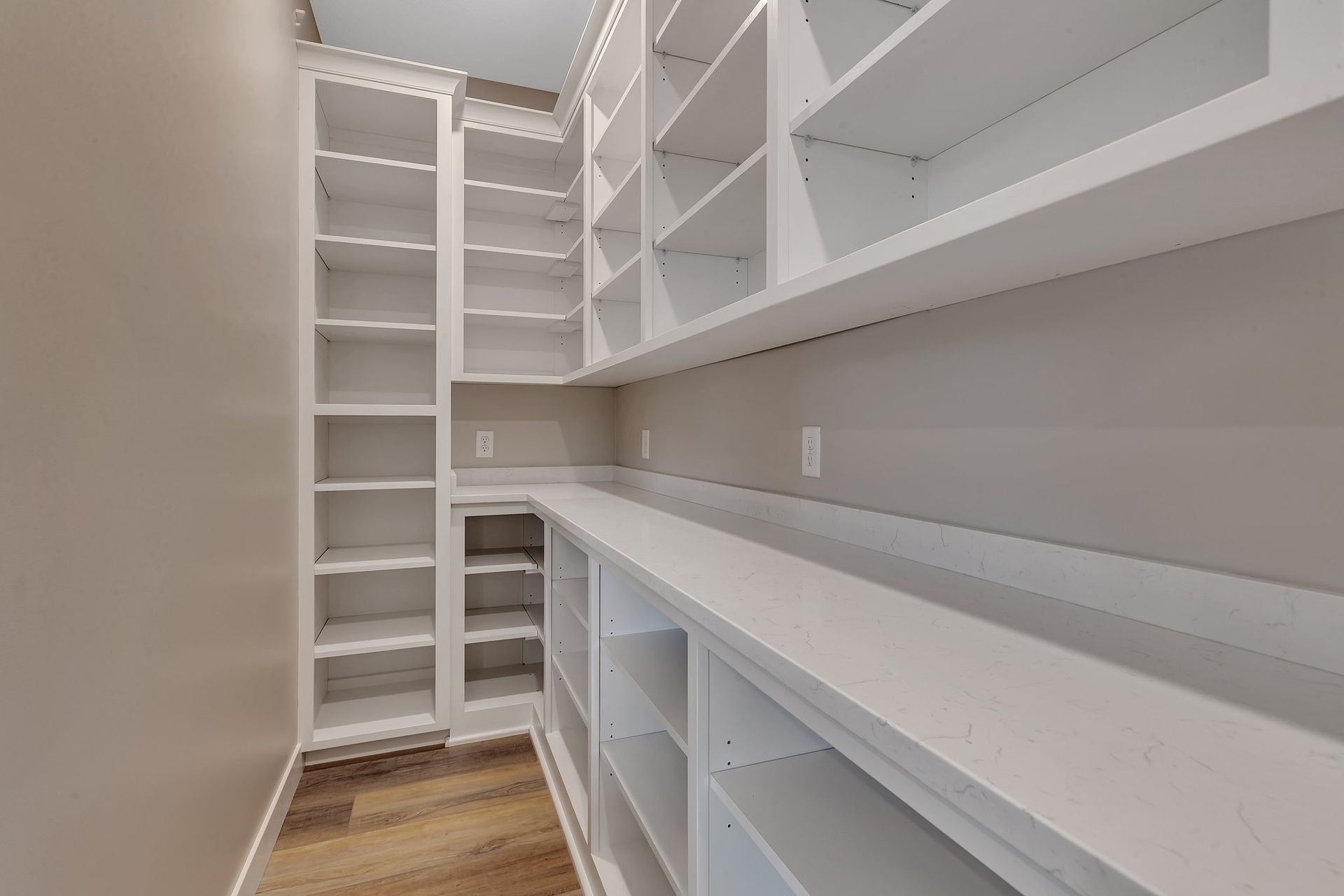 A walk in closet with lots of shelves and a wooden floor.