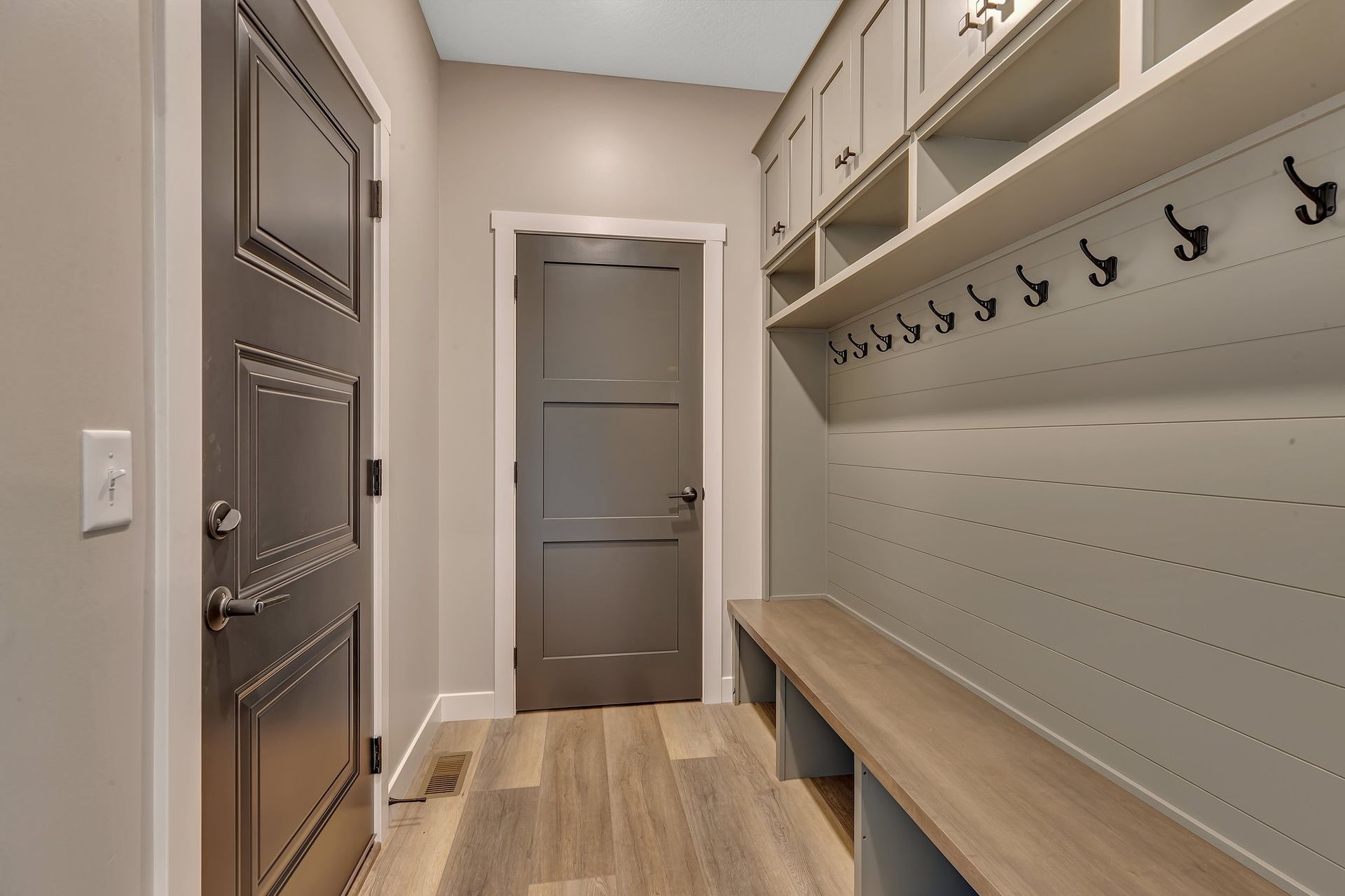 A hallway with a bench and hooks on the wall.