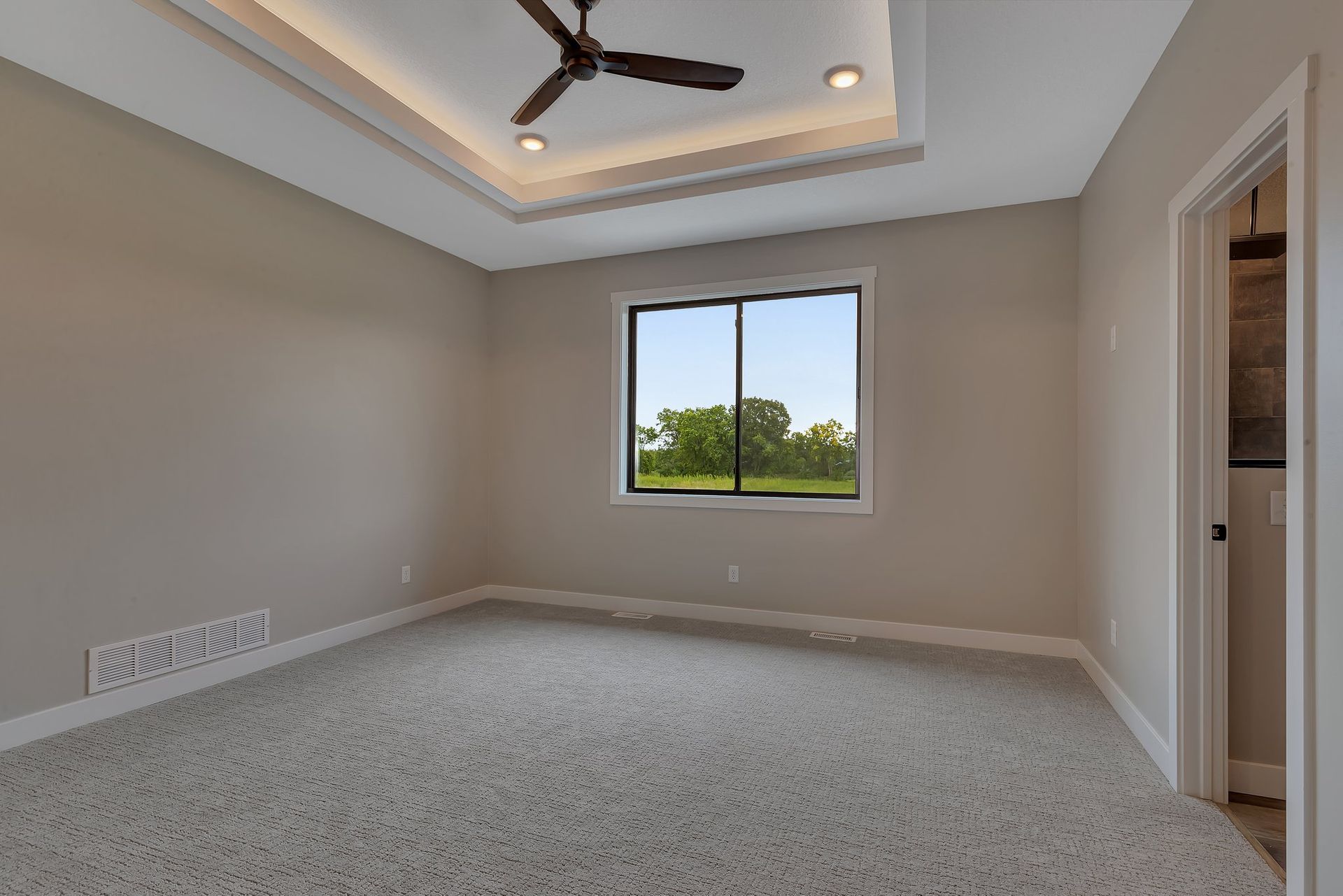 An empty bedroom with a ceiling fan and a window.