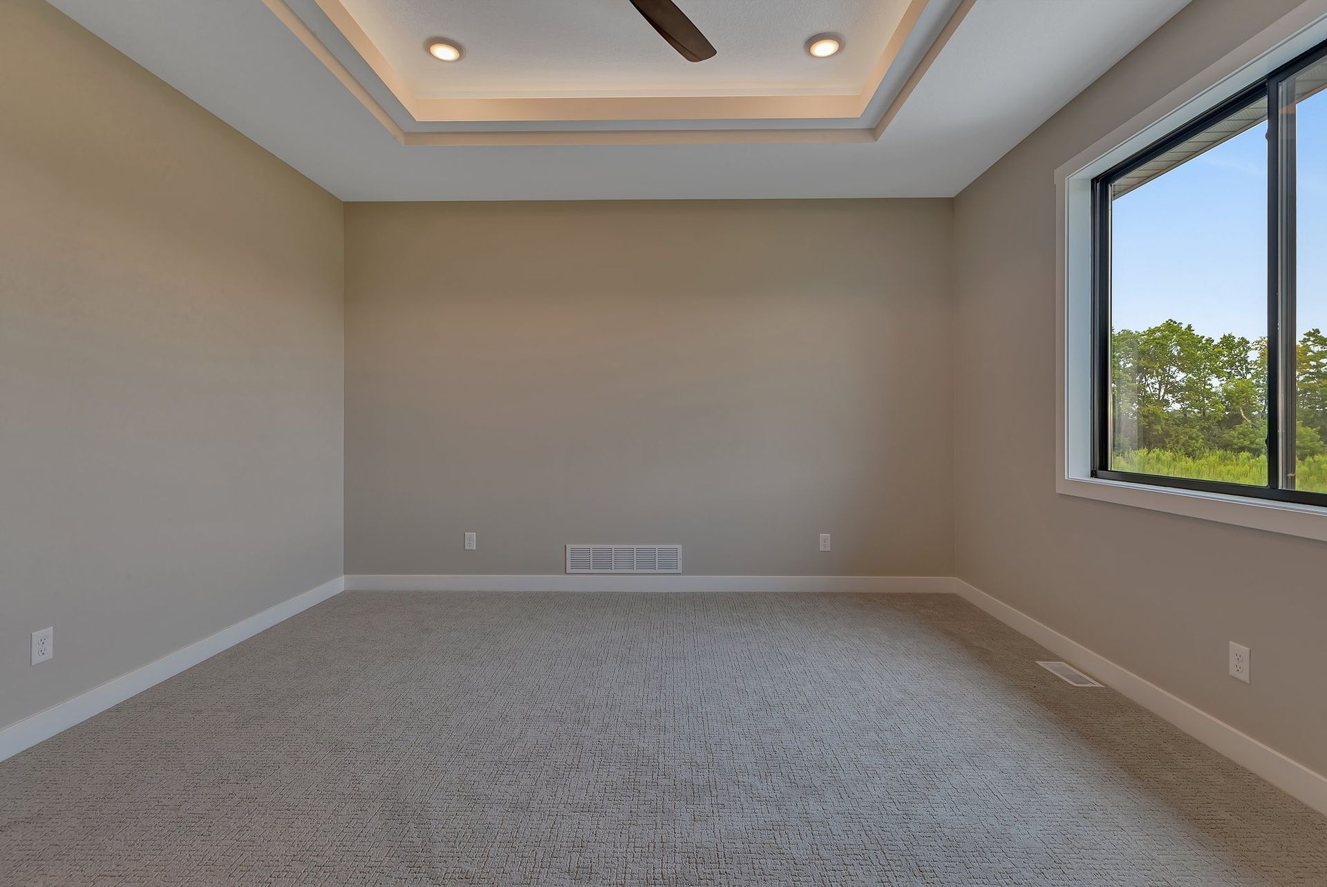 An empty bedroom with a ceiling fan and a large window.